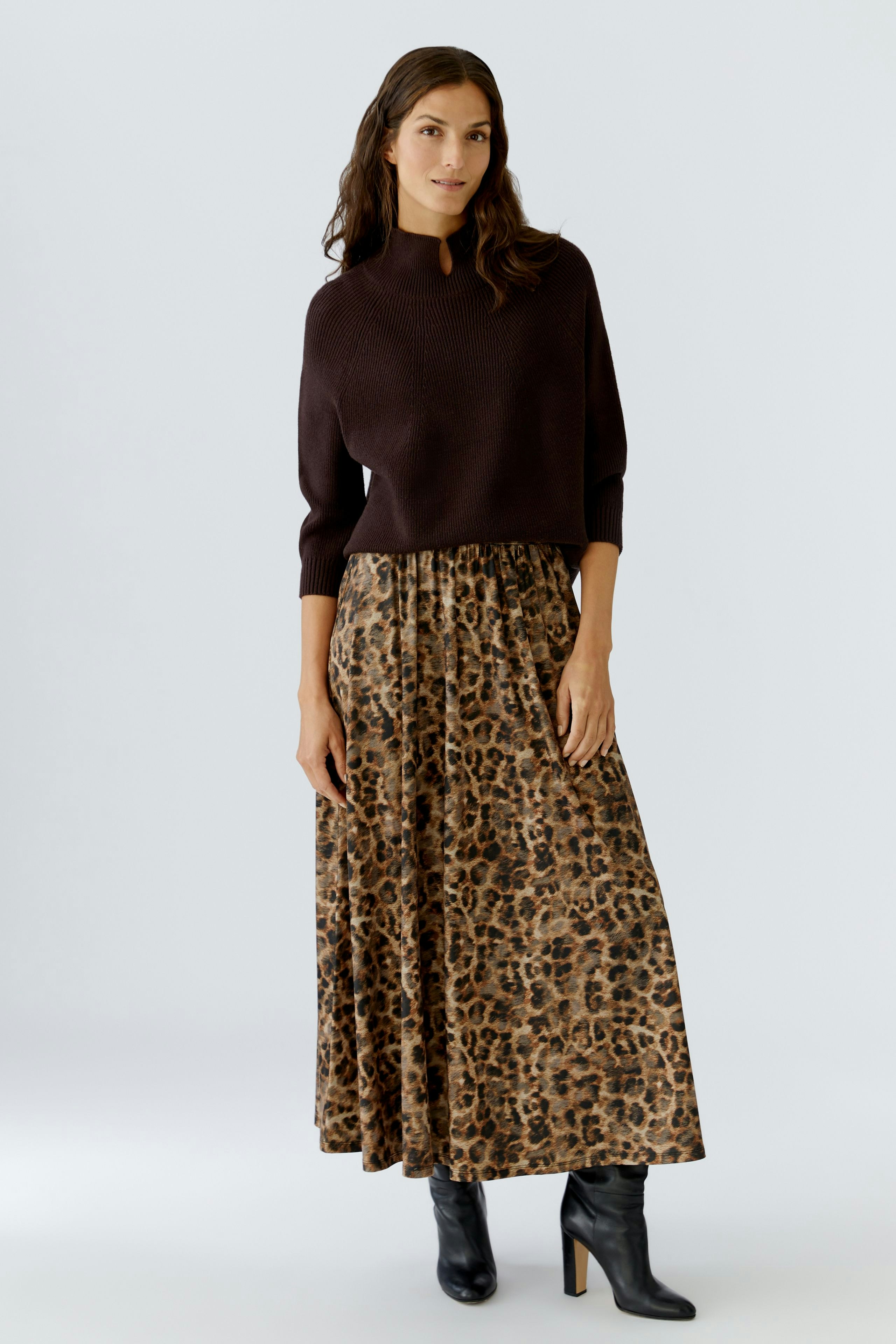 A-line skirt: Woman in a brown pullover and a leopard print A-line skirt stands confidently.