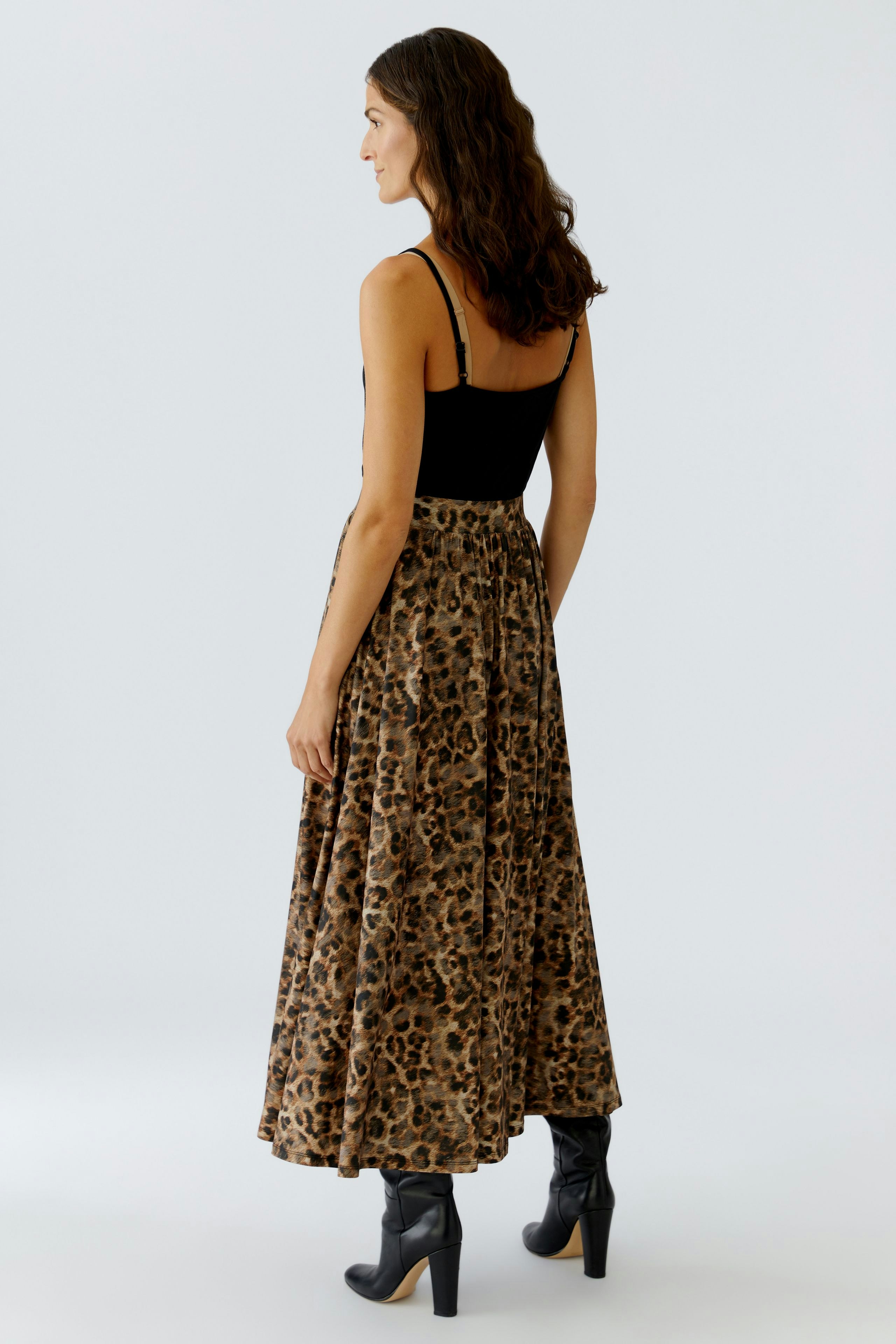 A-line skirt: Woman in a black top and a flowing leopard print skirt, showcasing a relaxed style.