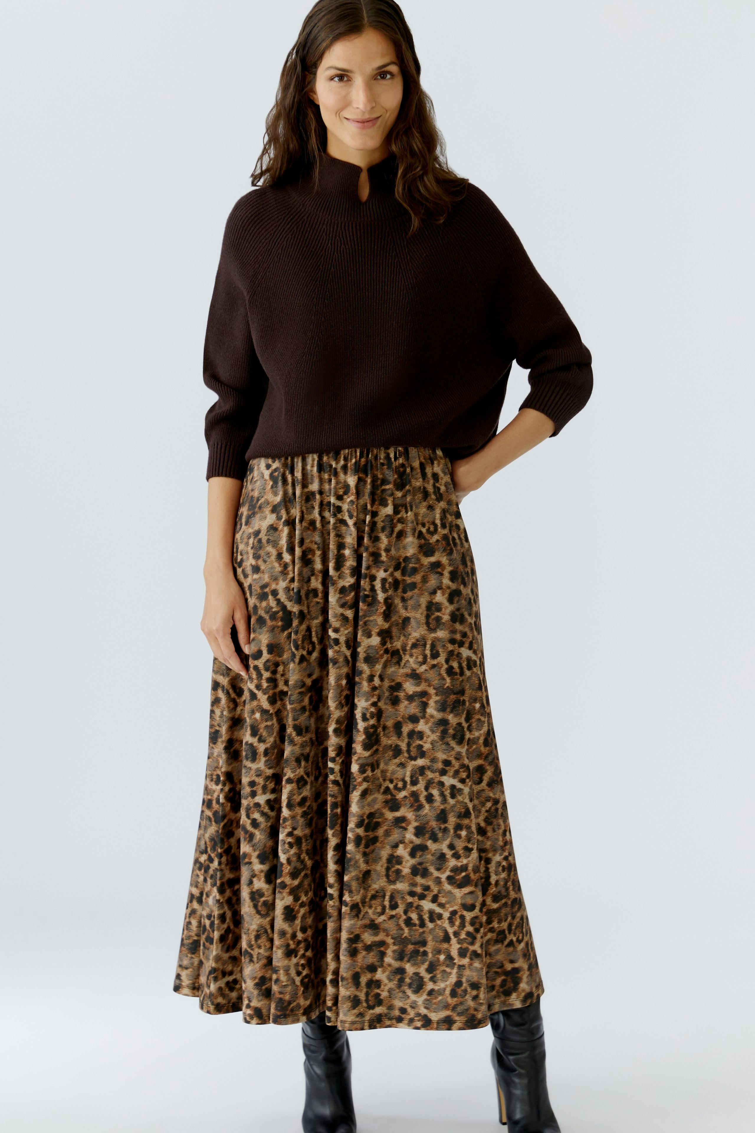 A-line skirt: Woman in a brown pullover and a flowing leopard print skirt, standing confidently.