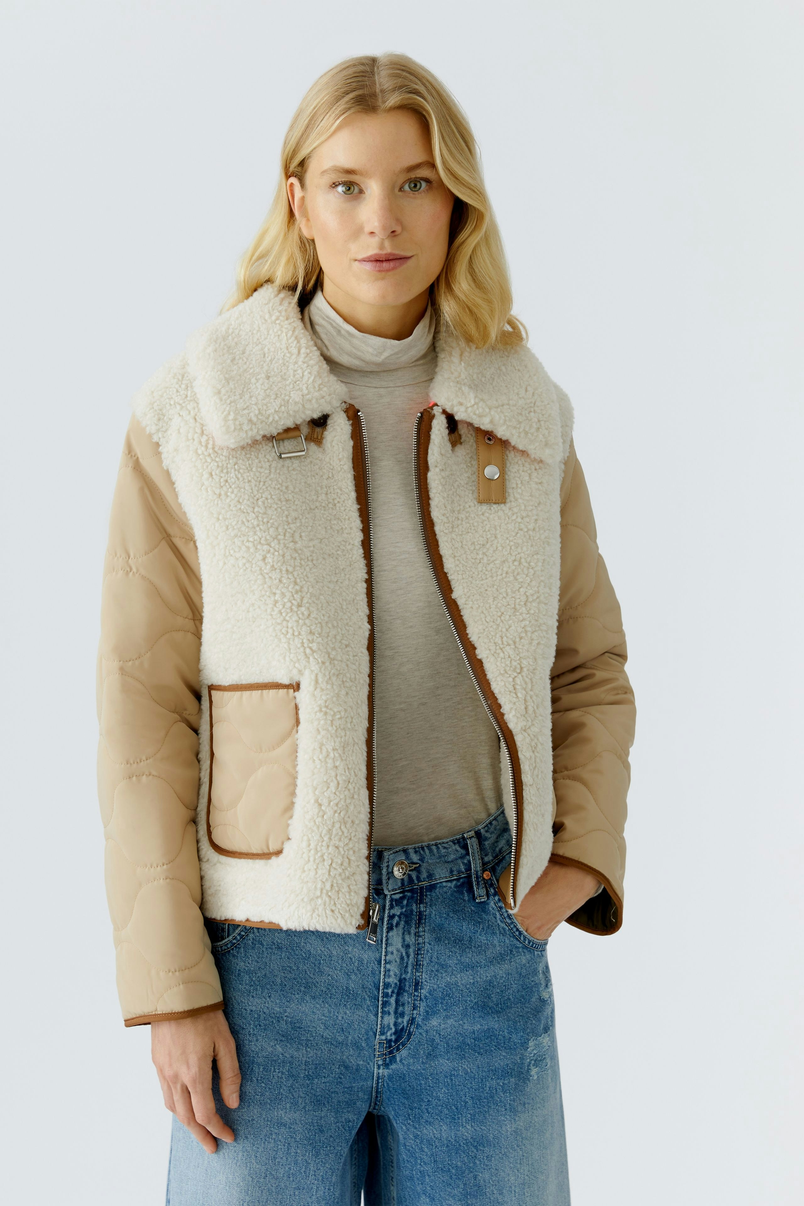 Casual women's outdoor jacket: A woman in a cozy, beige and cream jacket with a fluffy collar.