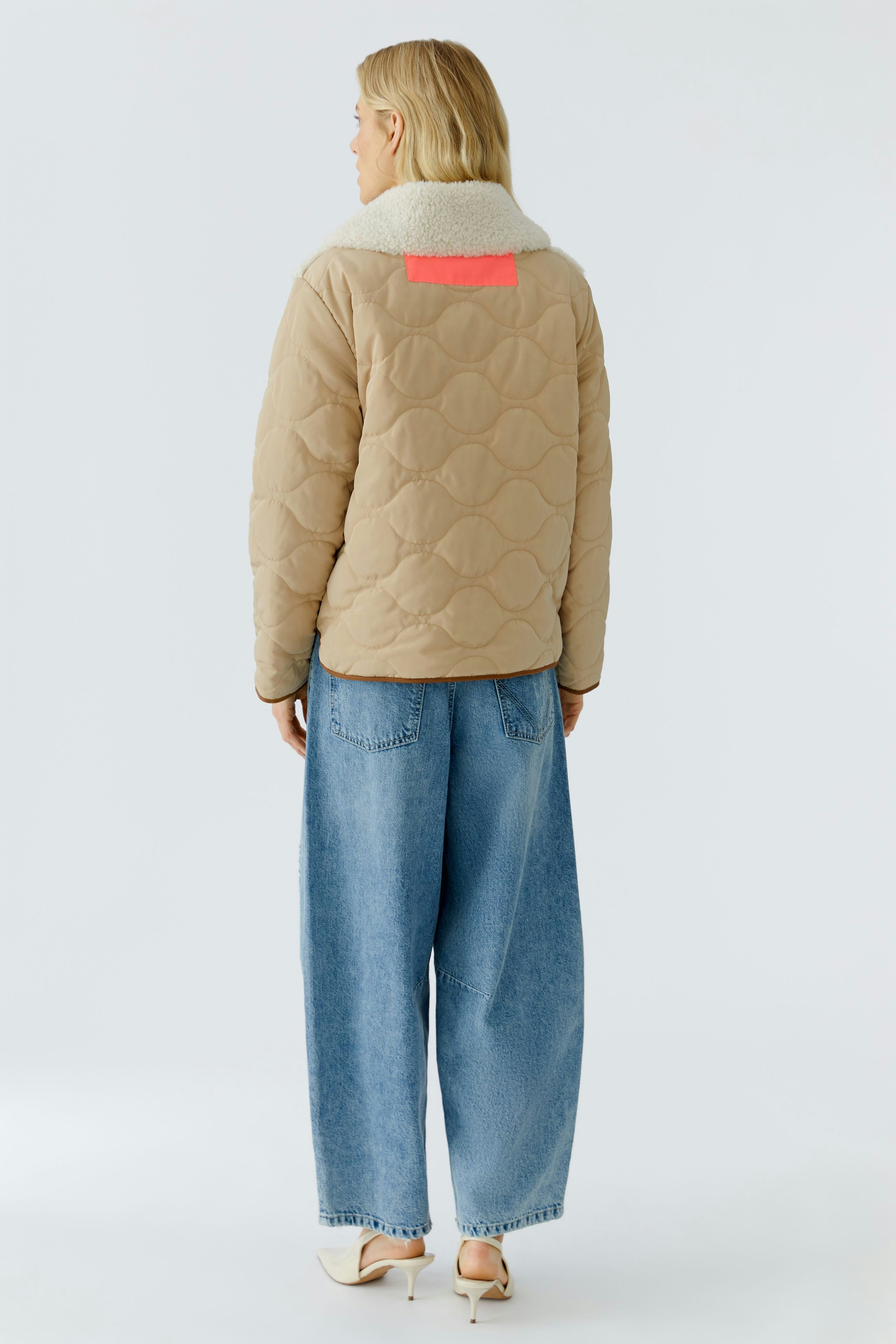 Casual women's outdoor jacket: A woman in a beige quilted jacket with a cozy collar and relaxed fit.