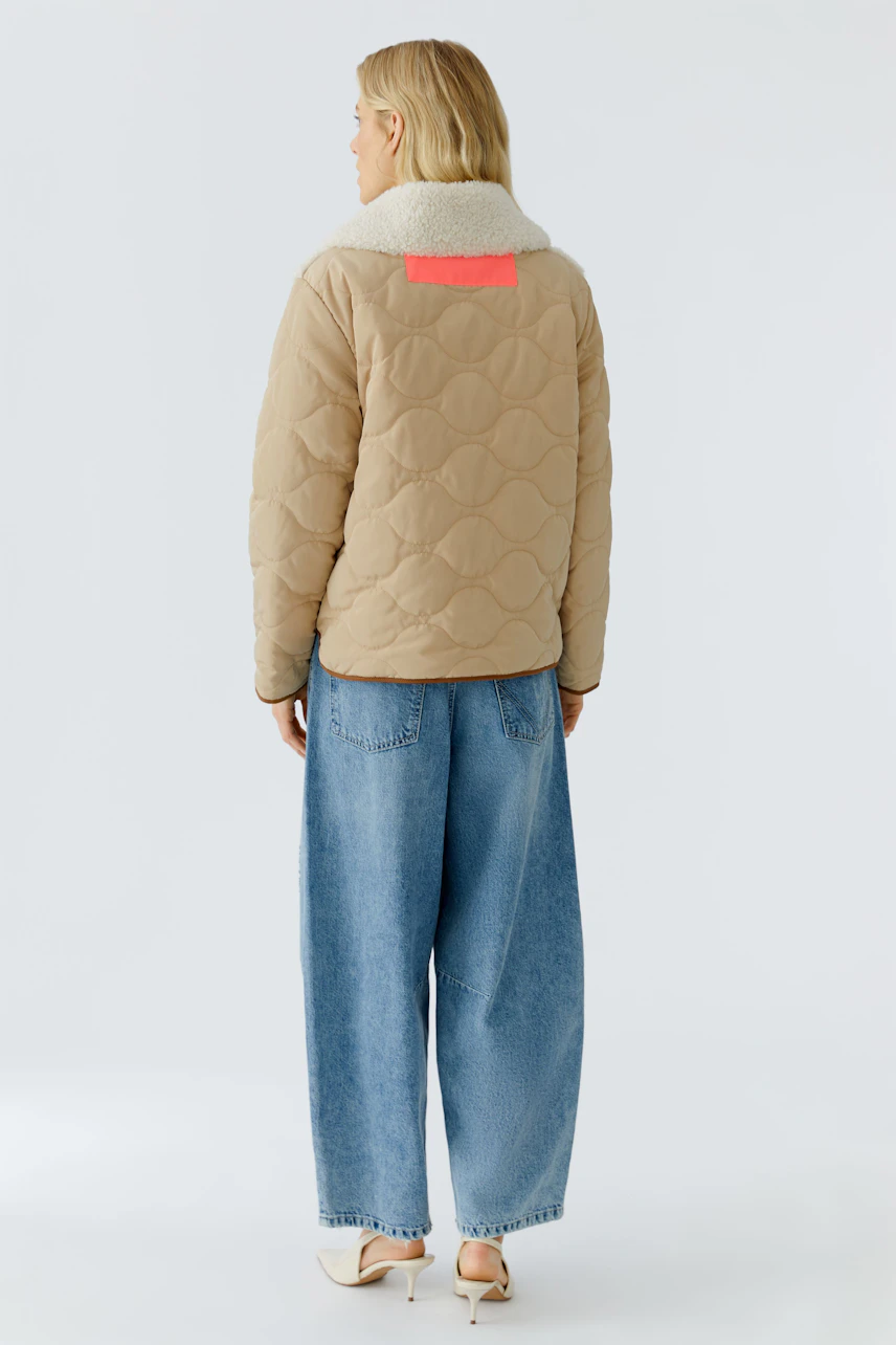 Casual women's outdoor jacket: A woman in a beige quilted jacket with a cozy collar and relaxed fit.
