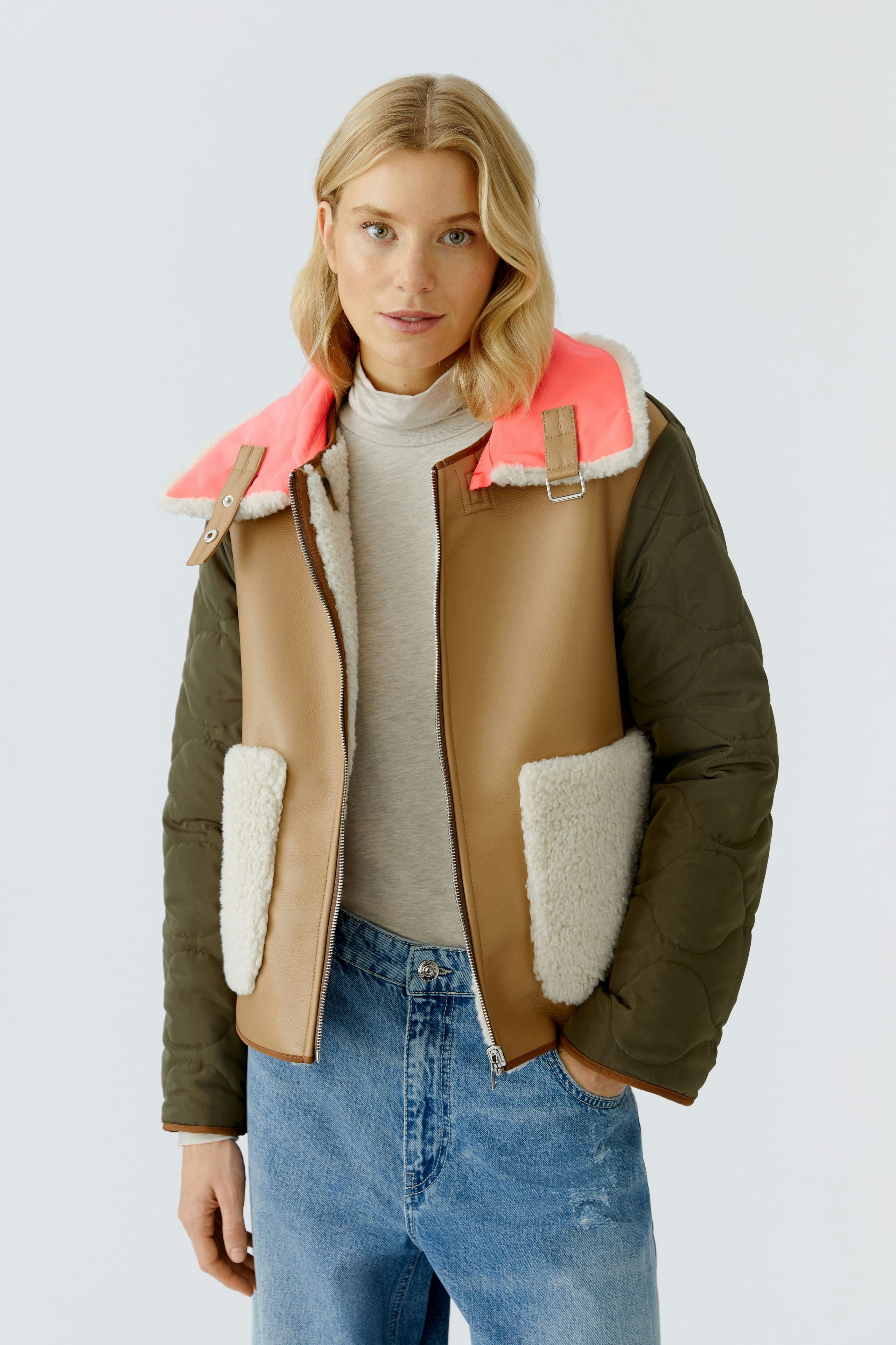 Stylish outdoor jacket: Woman in a brown and green jacket with a pink collar and cozy pockets.