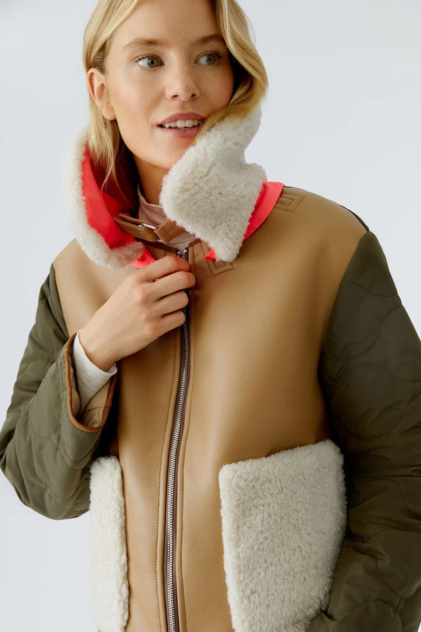 Stylish outdoor jacket: Woman in a brown and green jacket with a cozy collar and pockets.