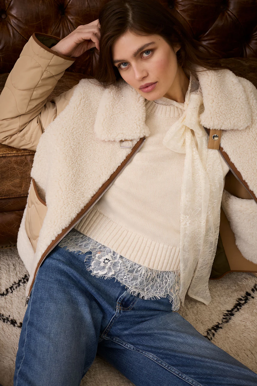 Casual outdoor jacket: Young woman in a beige outdoor jacket with a cozy sweater and jeans.