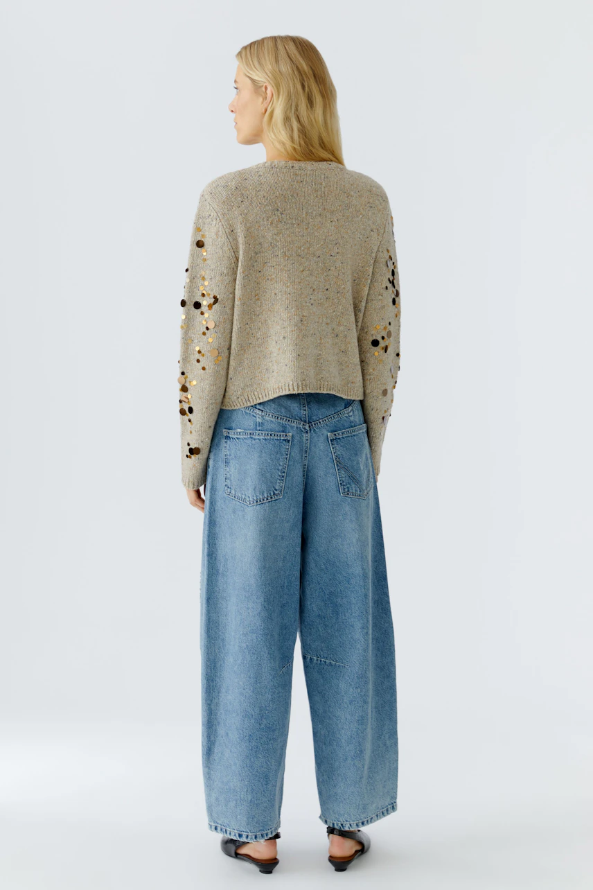 Casual women's cardigan: A woman in a light brown knitted cardigan with decorative details.