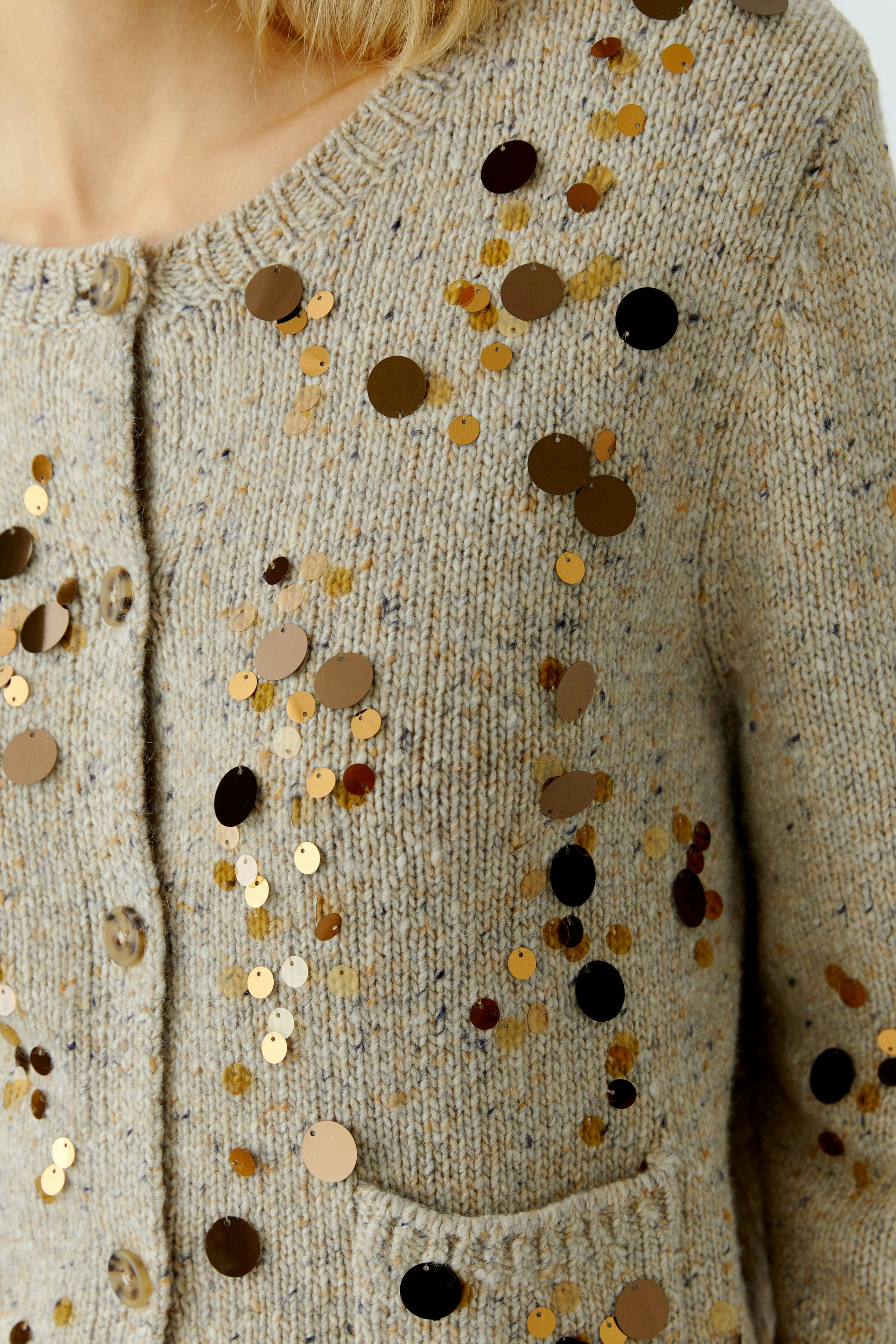 Casual women's cardigan: Close-up of a woman in a beige cardigan with sequins and pockets.