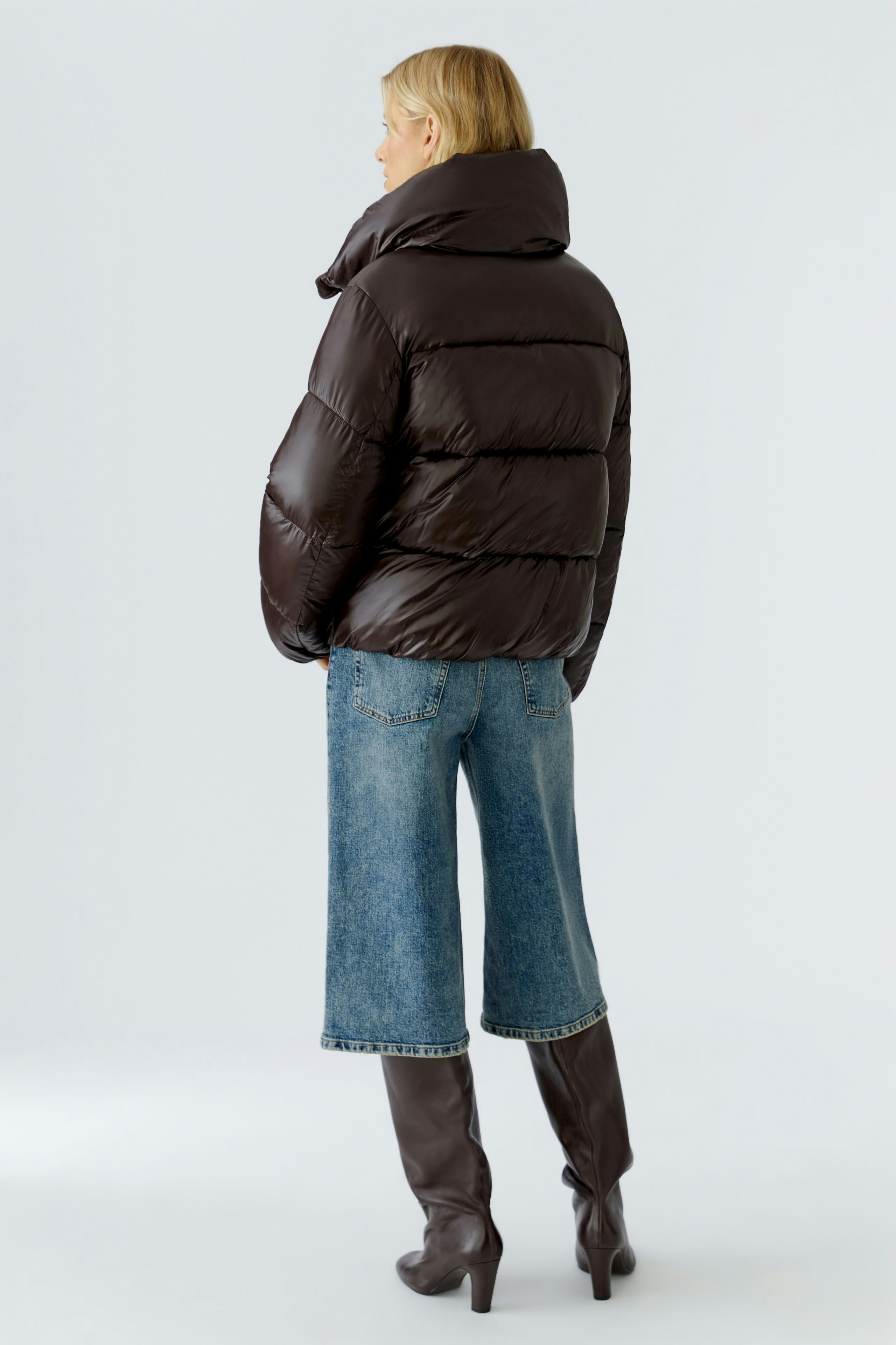 Stylish women's outdoor jacket: A woman in a brown puffer jacket paired with denim culottes.