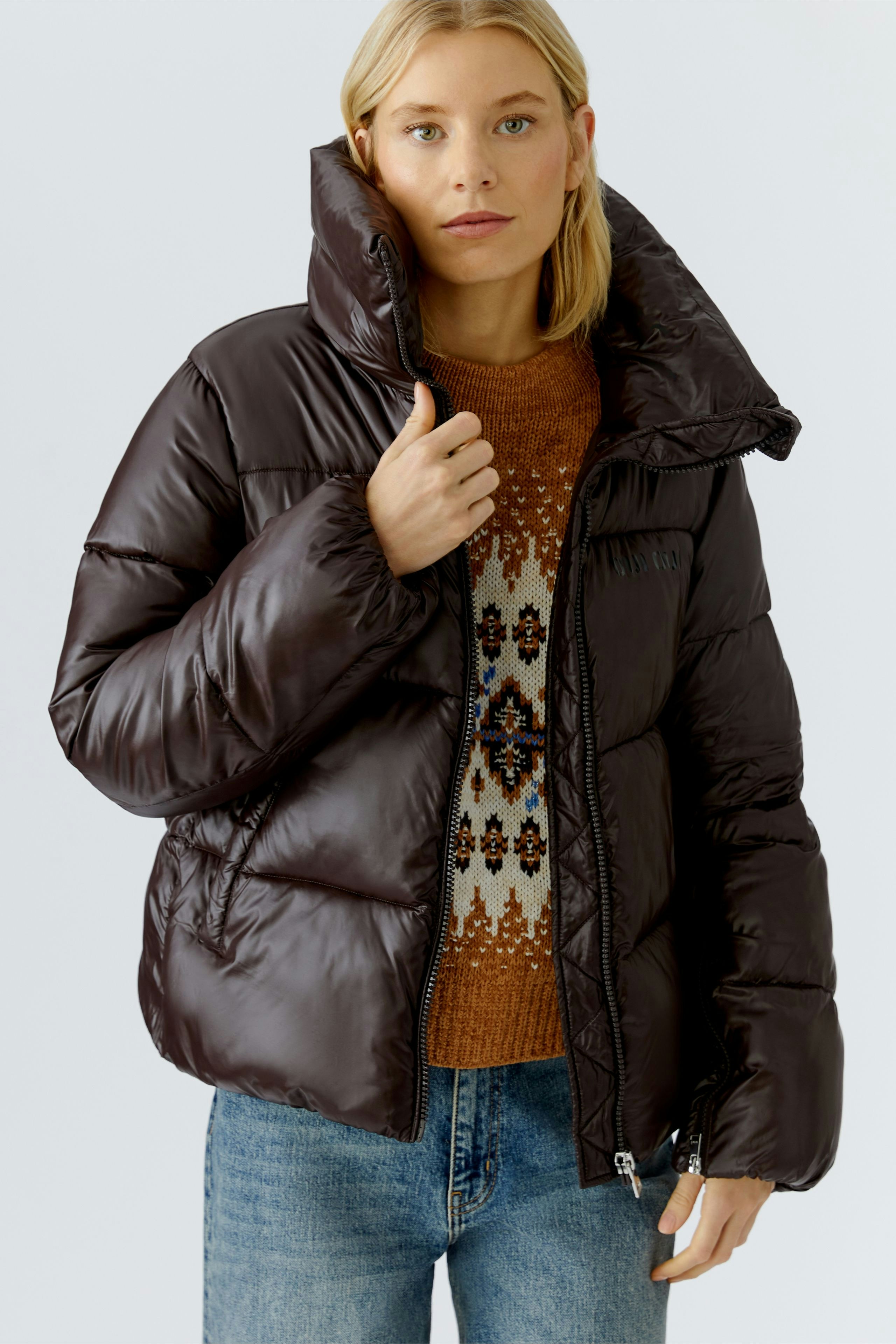 Stylish outdoor jacket: Woman in a brown puffer jacket with a high collar, paired with a cozy pullover.