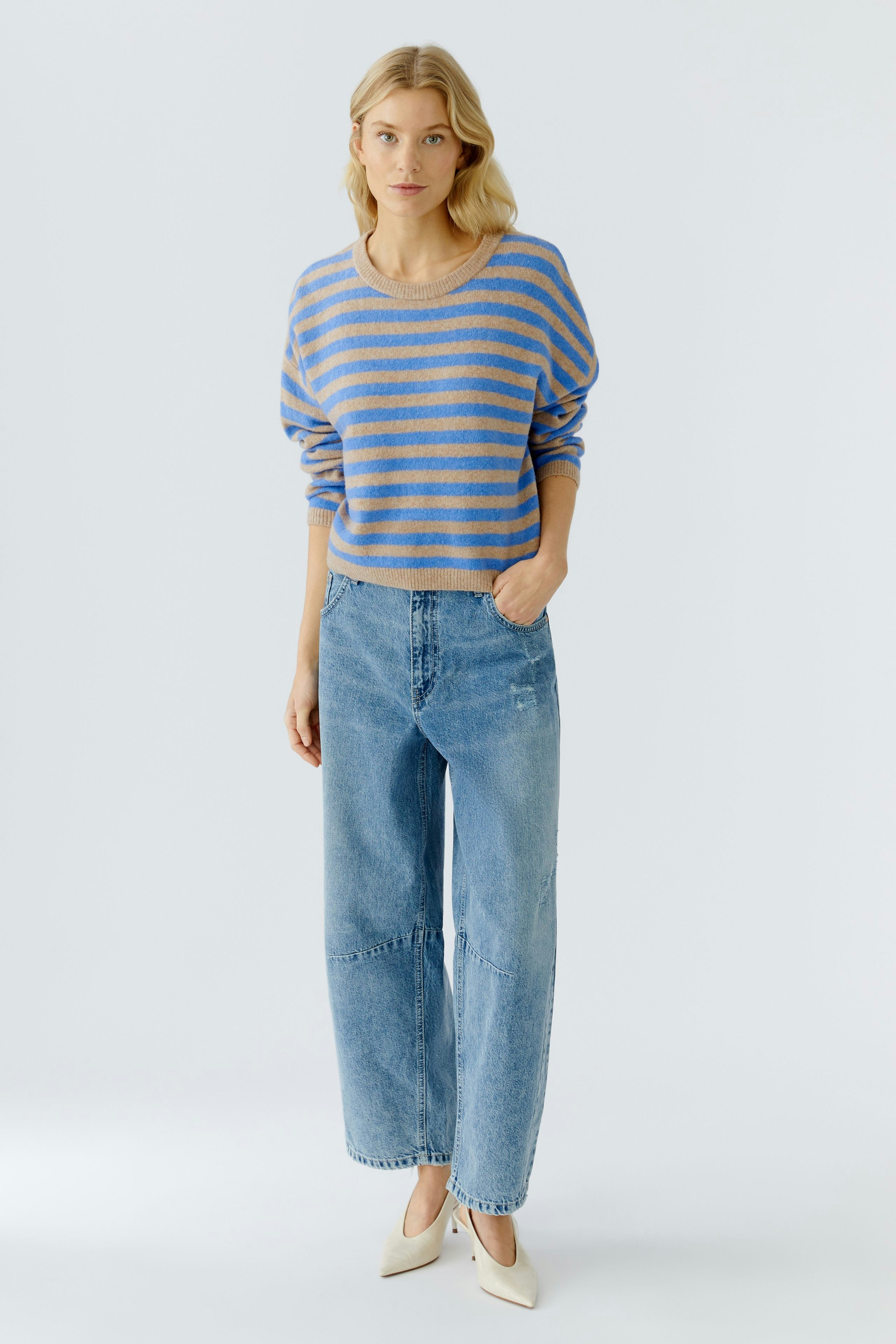 Damen-Pullover: Frau in gestreiftem Pullover mit lässigen Jeans steht entspannt.