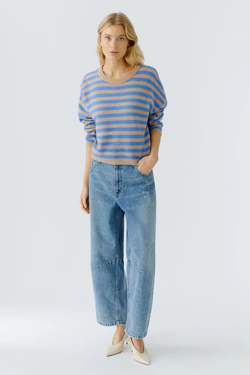 Damen-Pullover: Frau in gestreiftem Pullover mit lässigen Jeans steht entspannt.