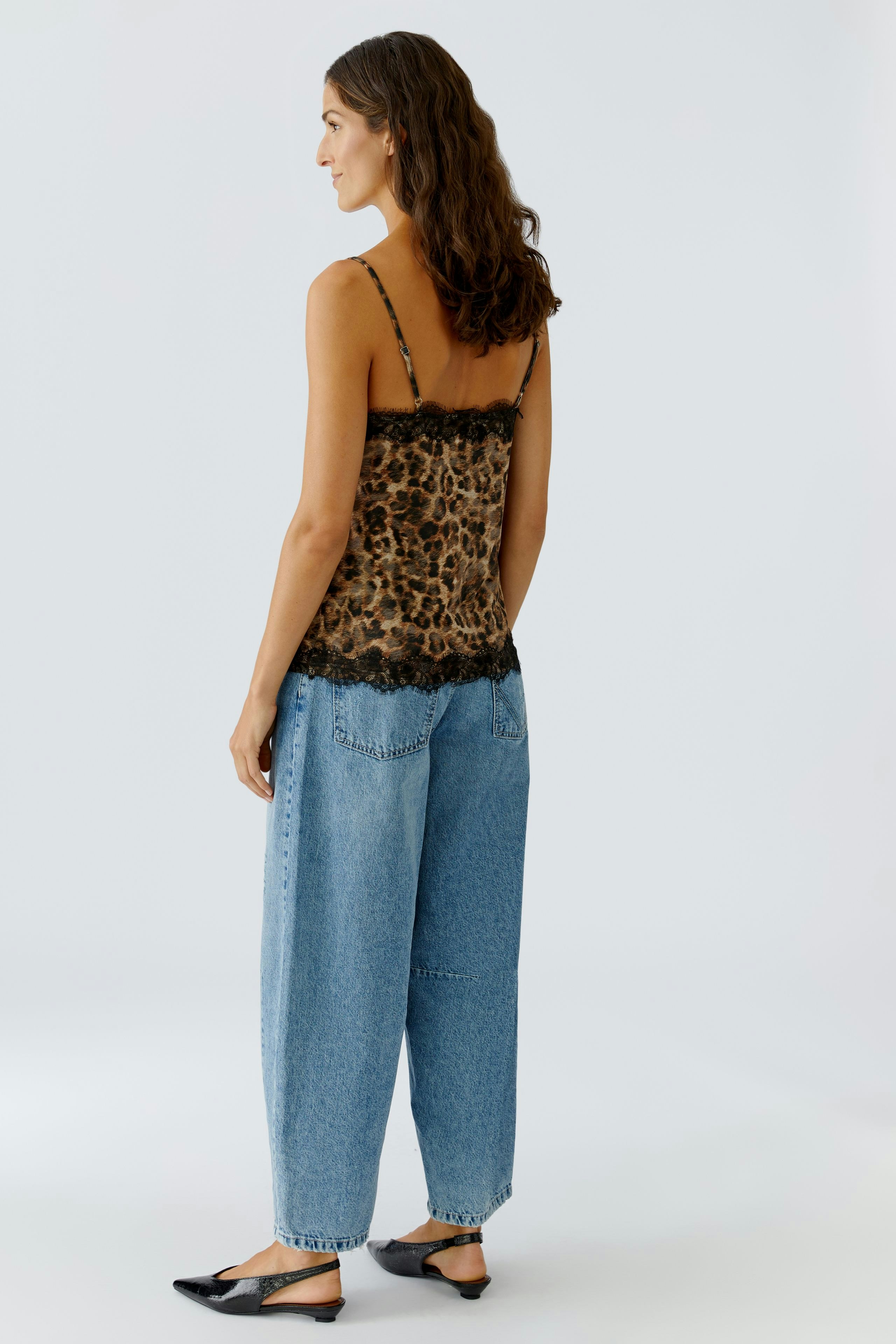 Casual women's top: A woman in a leopard print tank top with lace details and relaxed-fit jeans.