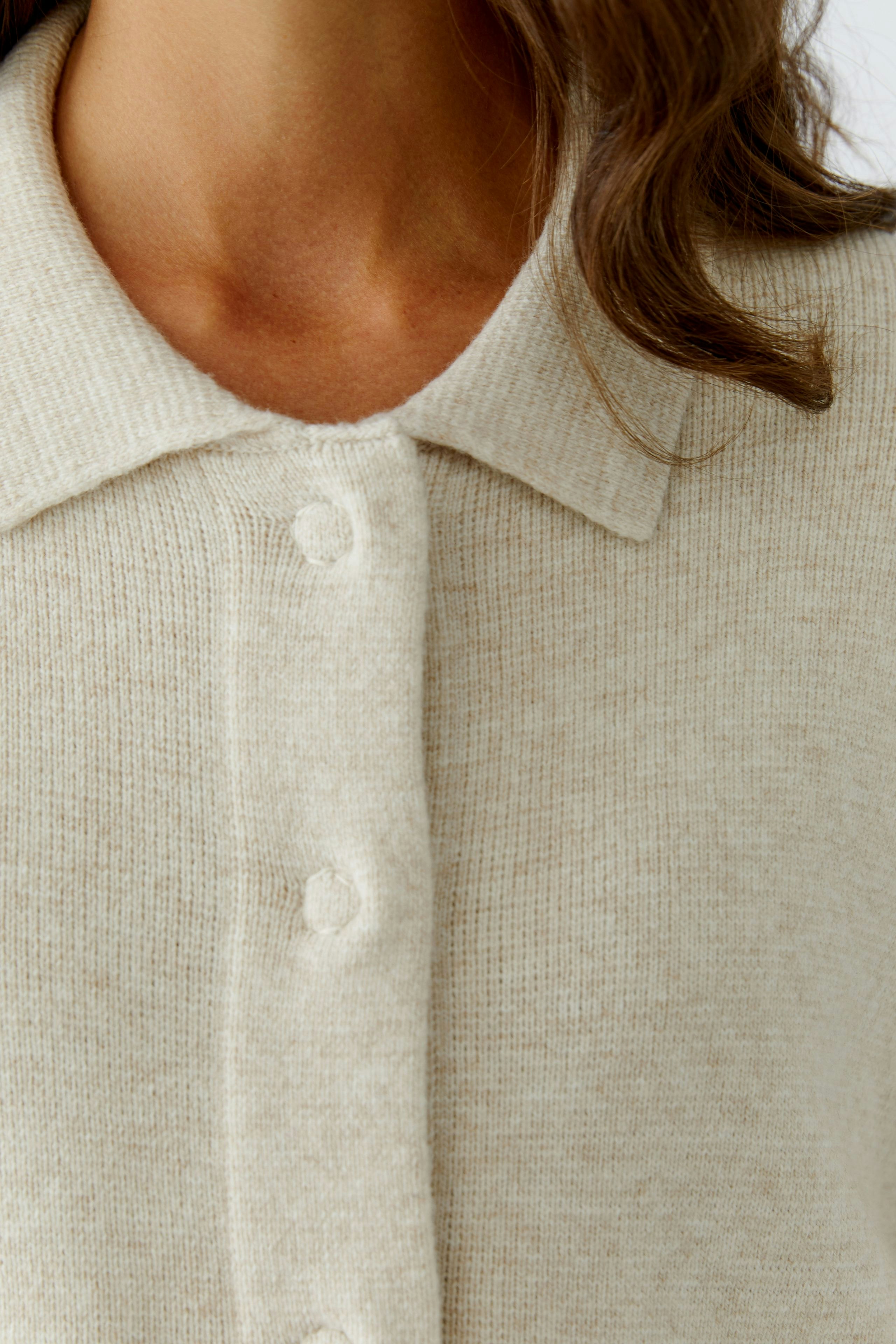 Casual women's cardigan: Close-up of a woman in a light beige cardigan with buttons.
