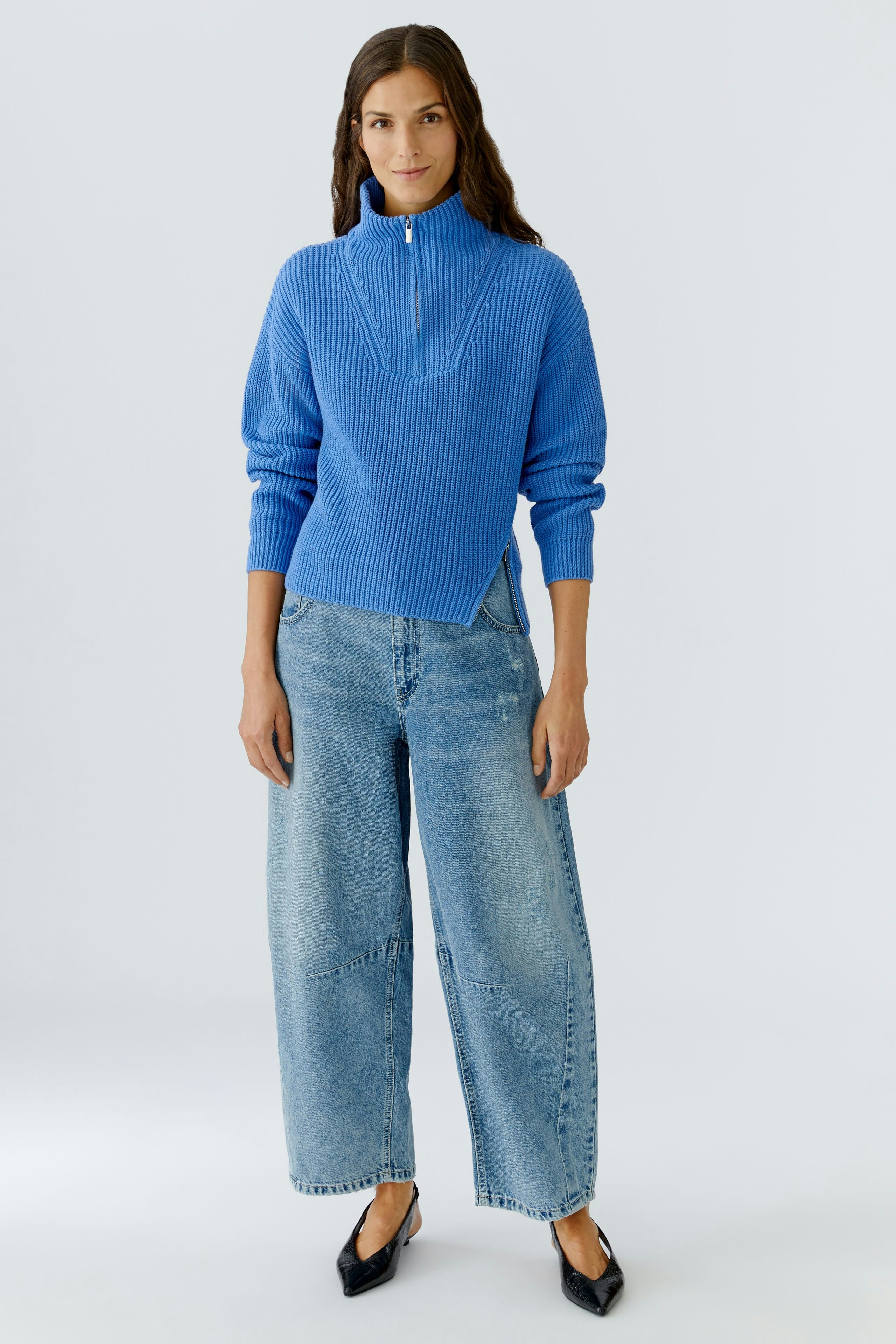 Casual women's pullover: Young woman in a blue ribbed pullover with a zip collar and relaxed-fit jeans.