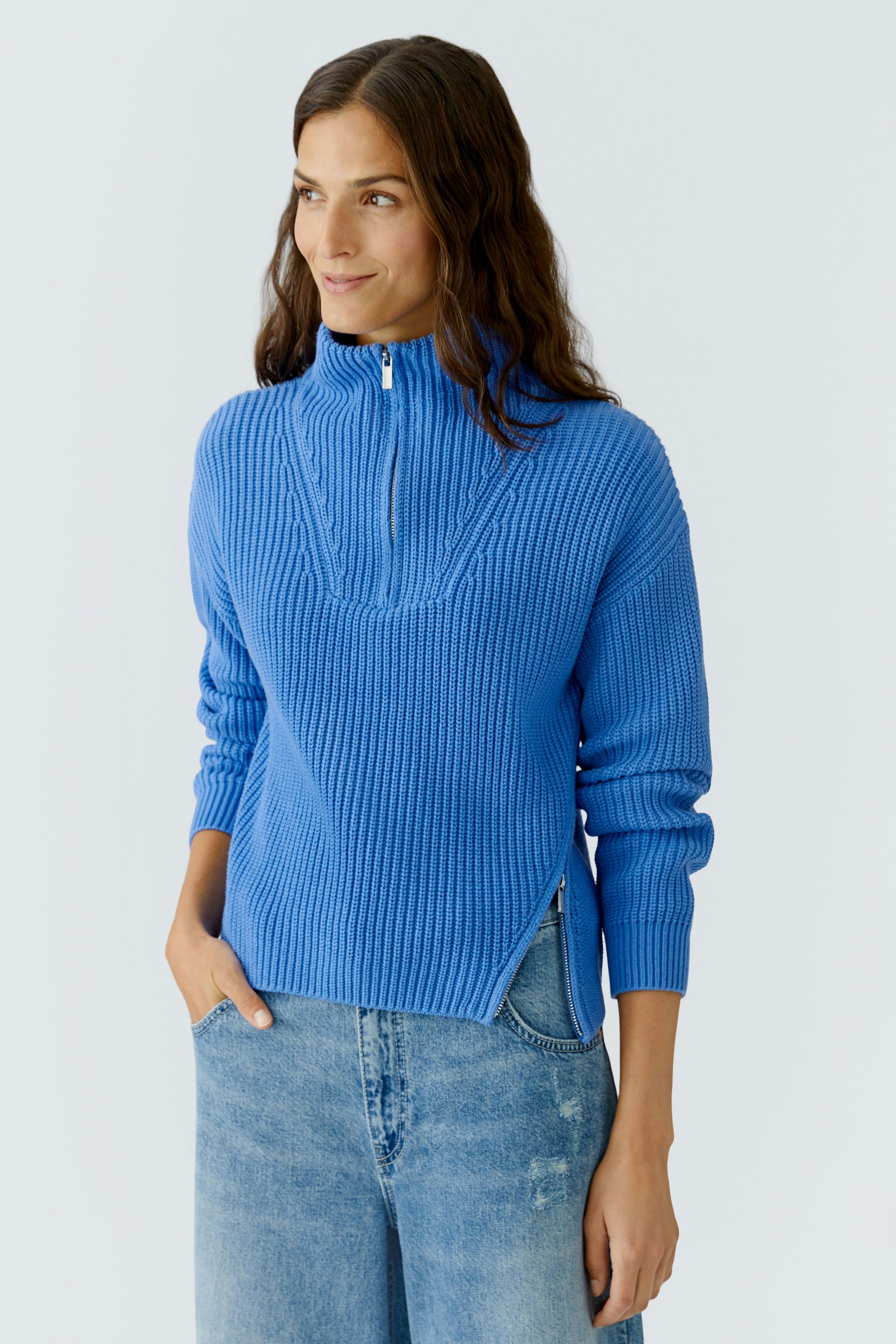 Casual women's pullover: Young woman in a blue ribbed pullover with a half-zip and relaxed fit.
