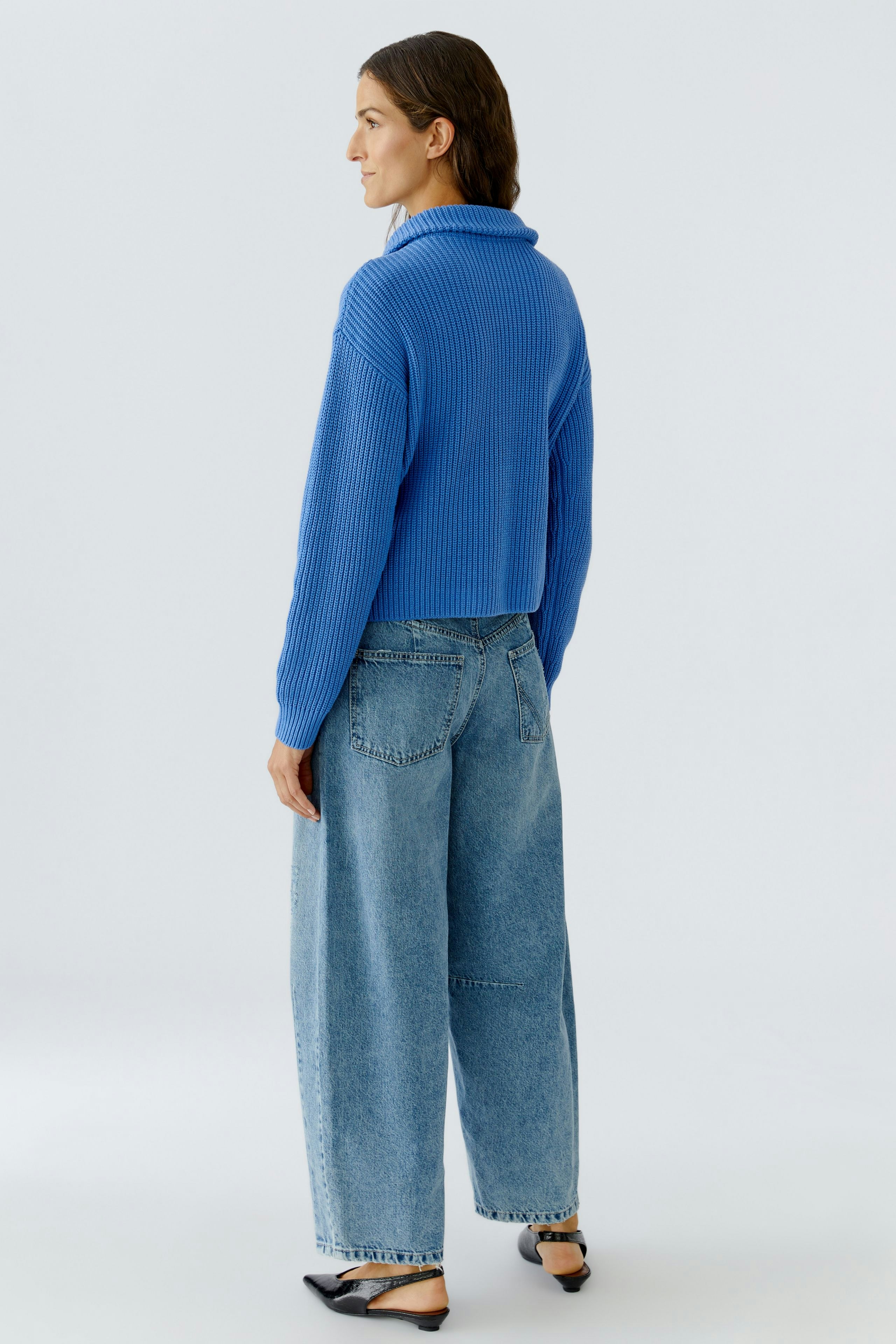 Casual women's pullover: A woman in a blue ribbed pullover paired with loose jeans, showcasing a relaxed style.