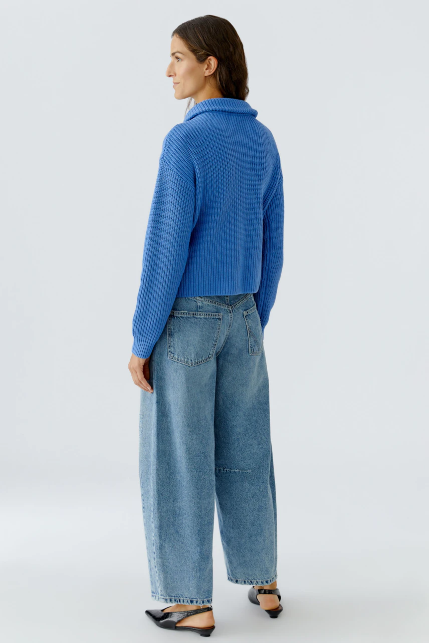 Damen-Pullover in Blau: Frau mit lässigem, strukturiertem Pullover und weiten Jeans von hinten.