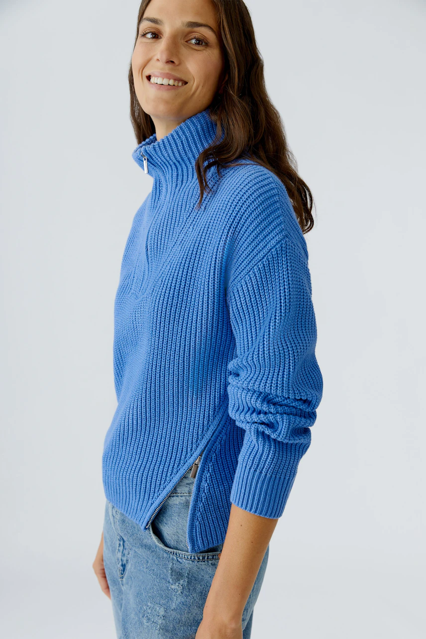 Damen-Pullover: Frau in blauem Strickpullover mit Stehkragen und lässigem Schnitt.