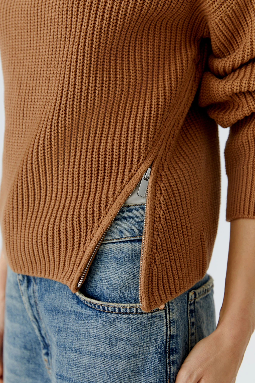 Casual women's pullover: A woman in a brown knitted pullover with a side zipper, paired with denim.