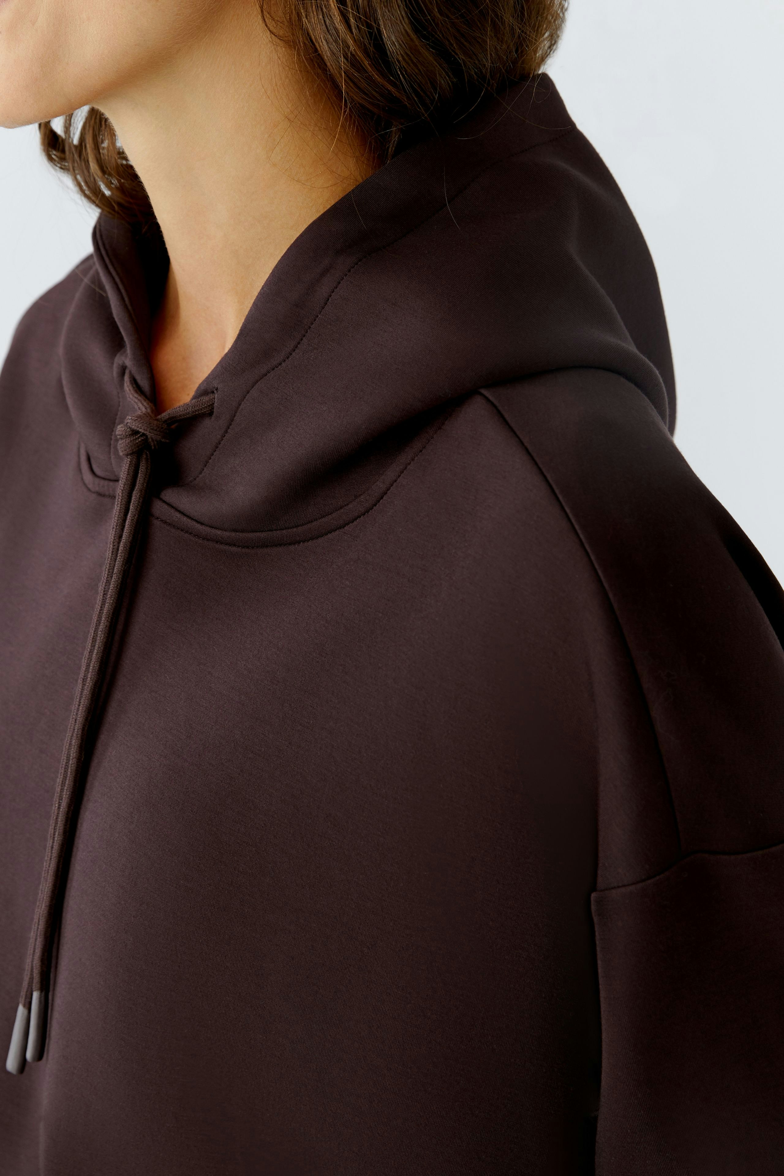 Casual women's hoodie: Close-up of a woman in a dark pullover with a hood, showcasing a relaxed style.