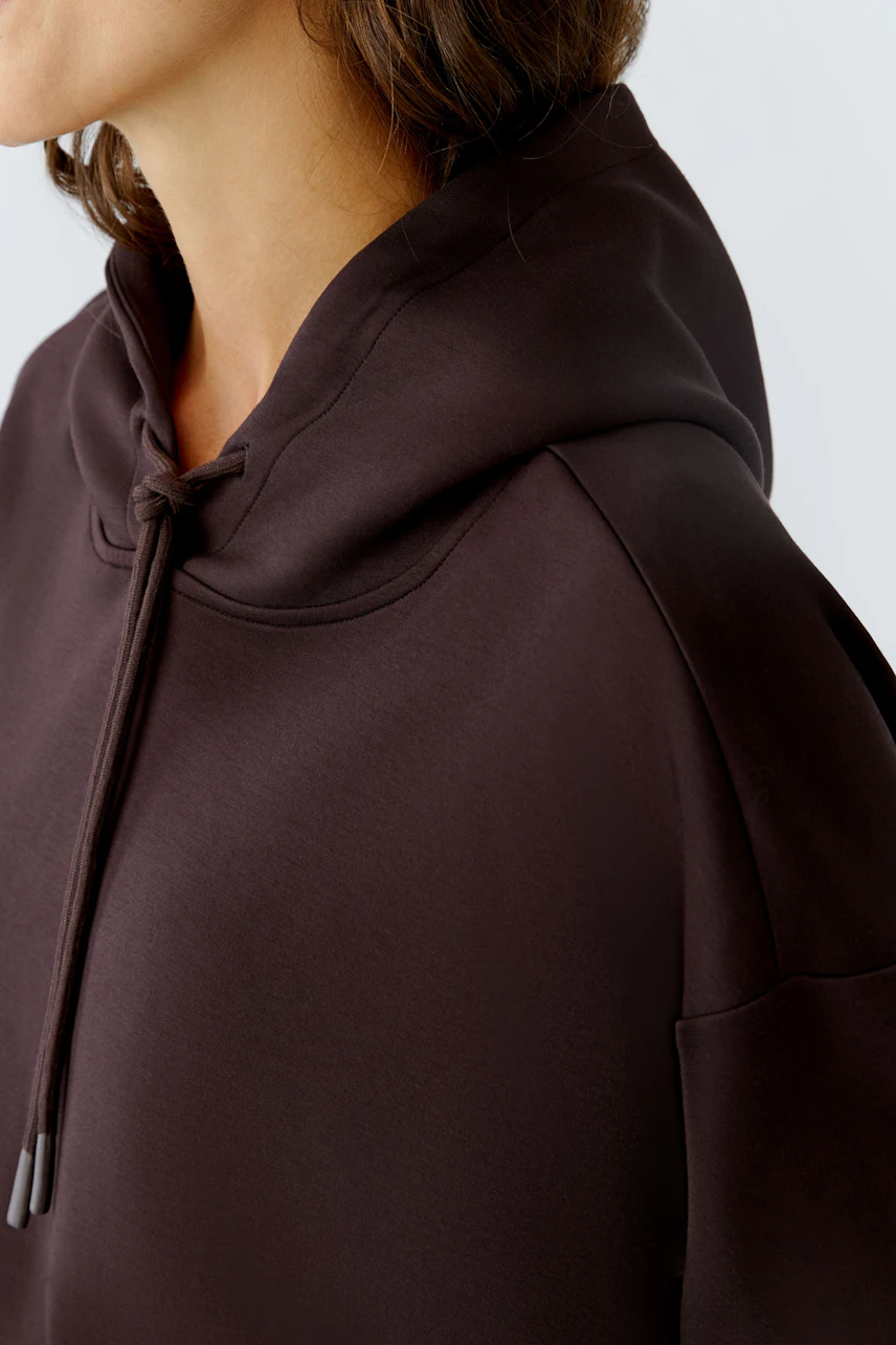 Casual women's hoodie: Close-up of a woman in a dark pullover with a hood, showcasing a relaxed style.