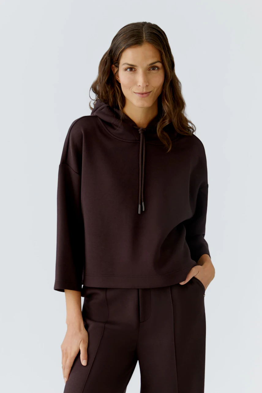 Casual women's pullover: Confident woman in a dark brown hoodie with a relaxed fit.