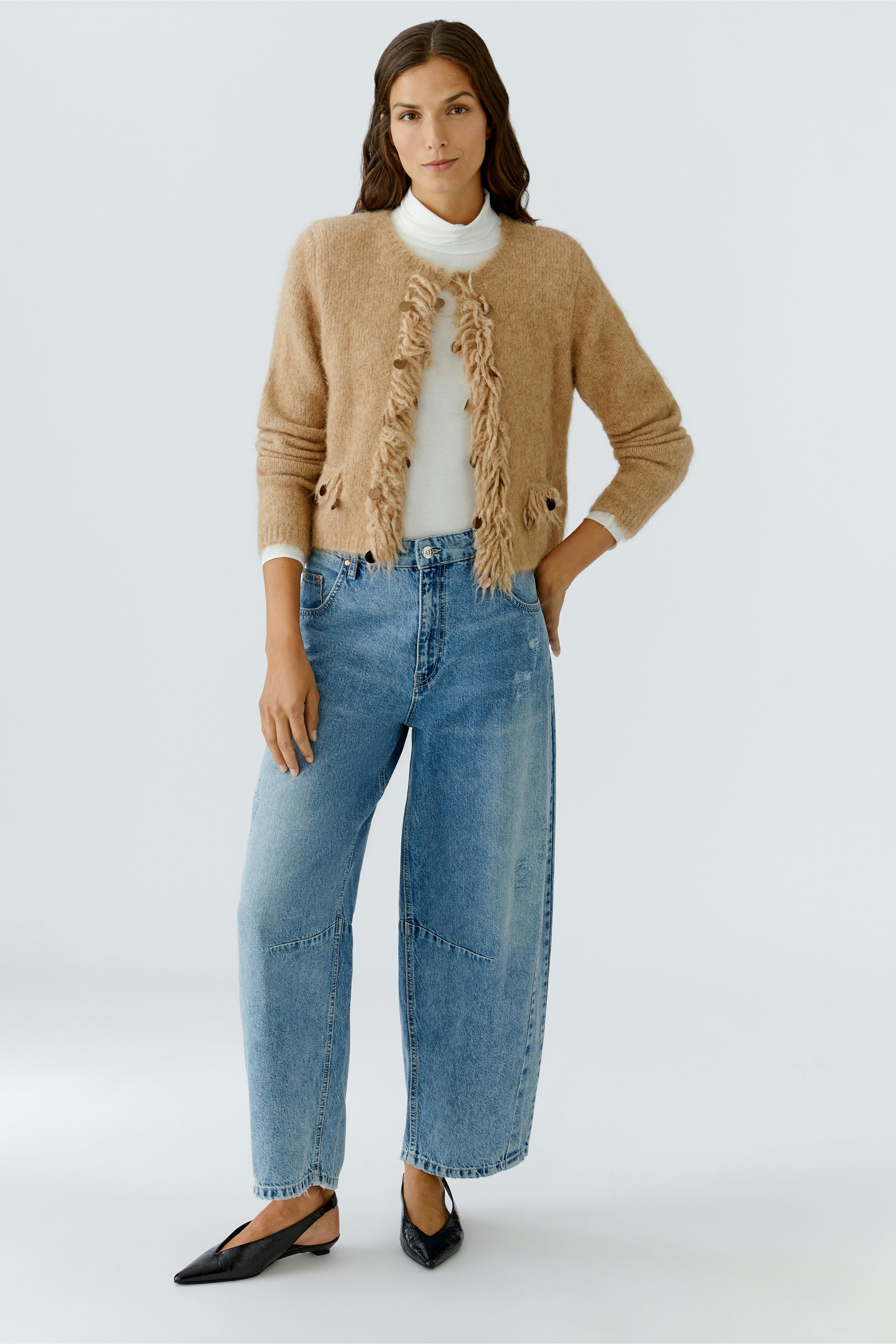 Cozy women's cardigan with fringe details, paired with relaxed jeans and stylish flats.