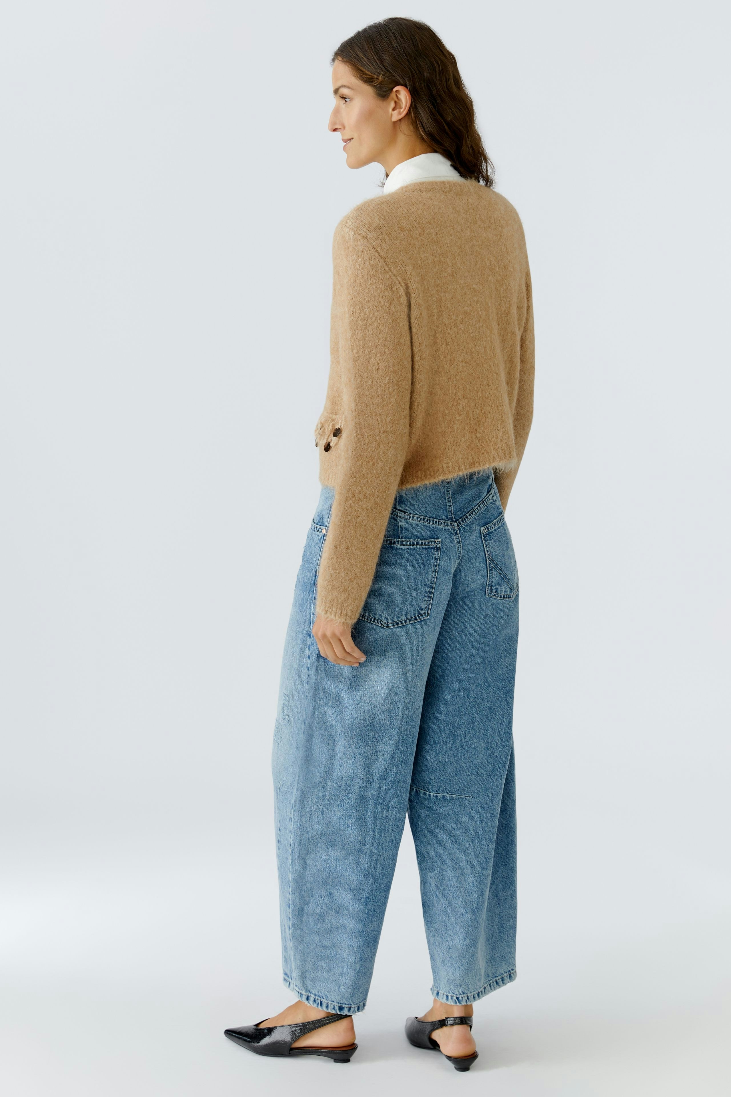 Casual women's cardigan: A woman in a light brown cardigan with a relaxed fit and wide jeans.