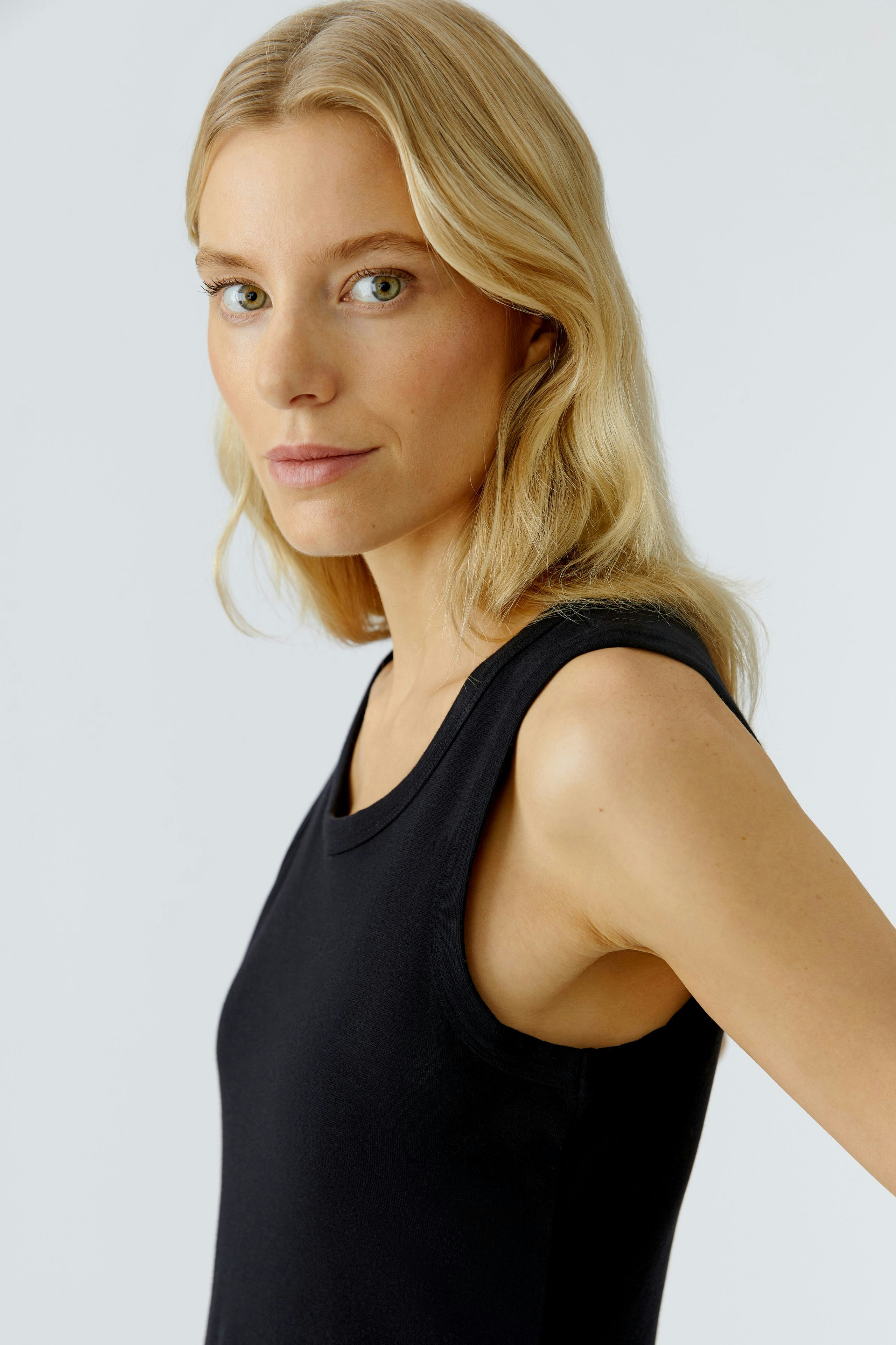 Casual black midi dress: Woman in a sleeveless design, showcasing a relaxed fit and modern style.