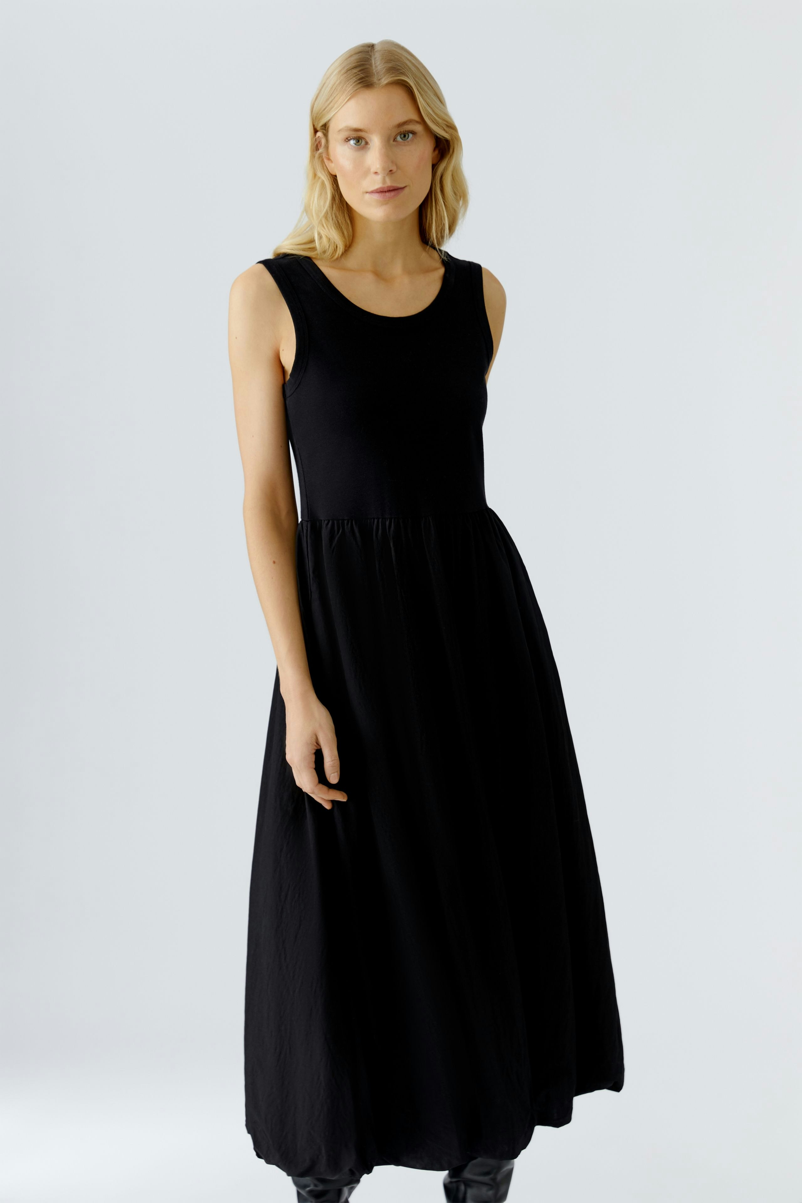Casual black midi dress: Woman in a sleeveless, flowy design, perfect for everyday wear.