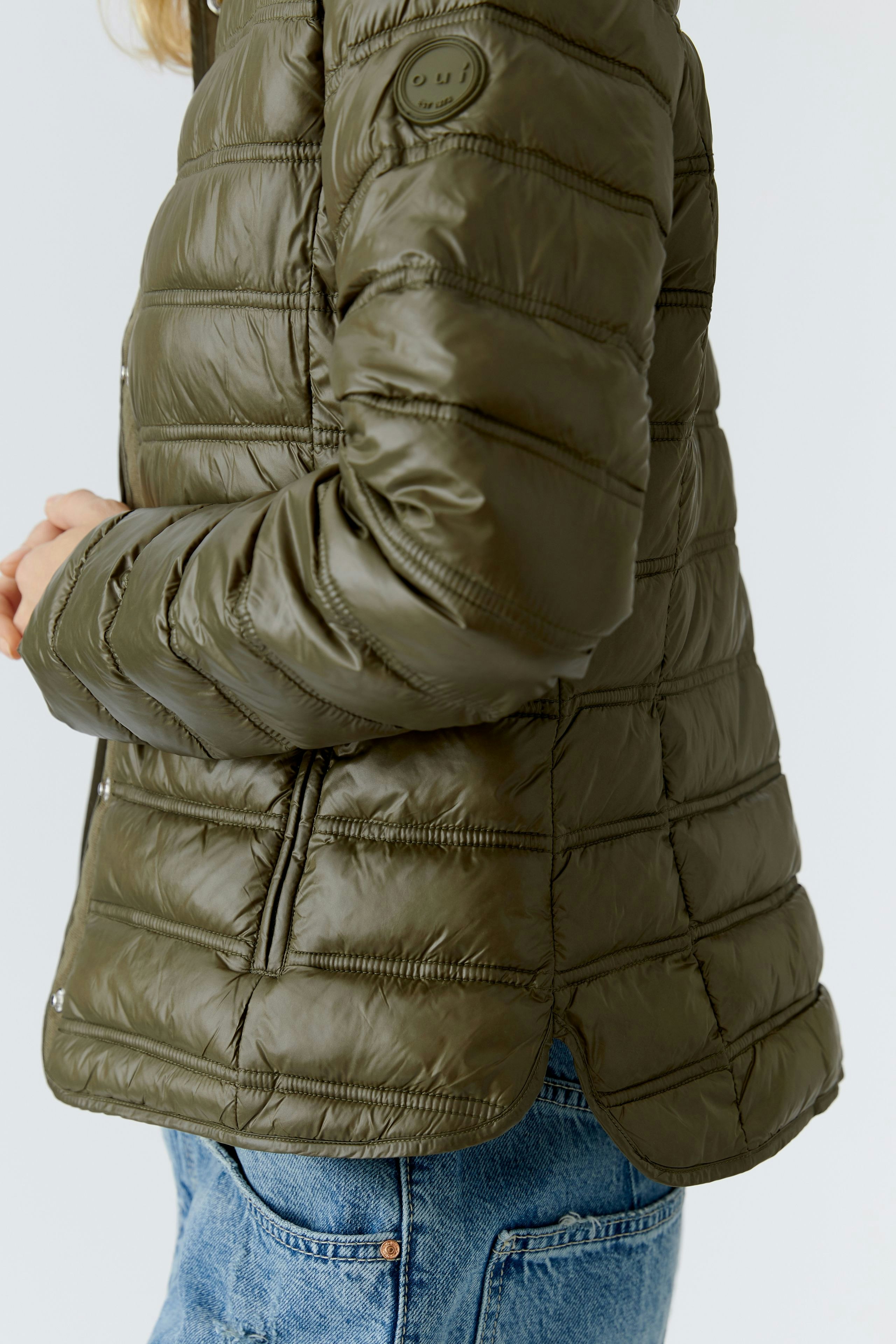 Lightweight outdoor jacket: Woman in a green puffer jacket with a relaxed fit, perfect for outdoor activities.