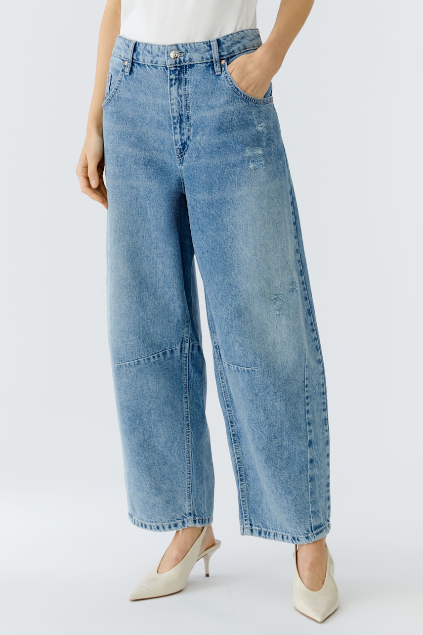 Bequeme Jeans Barrel: Frau trägt lässige, weite Jeans in hellem Denim, kombiniert mit eleganten Schuhen.