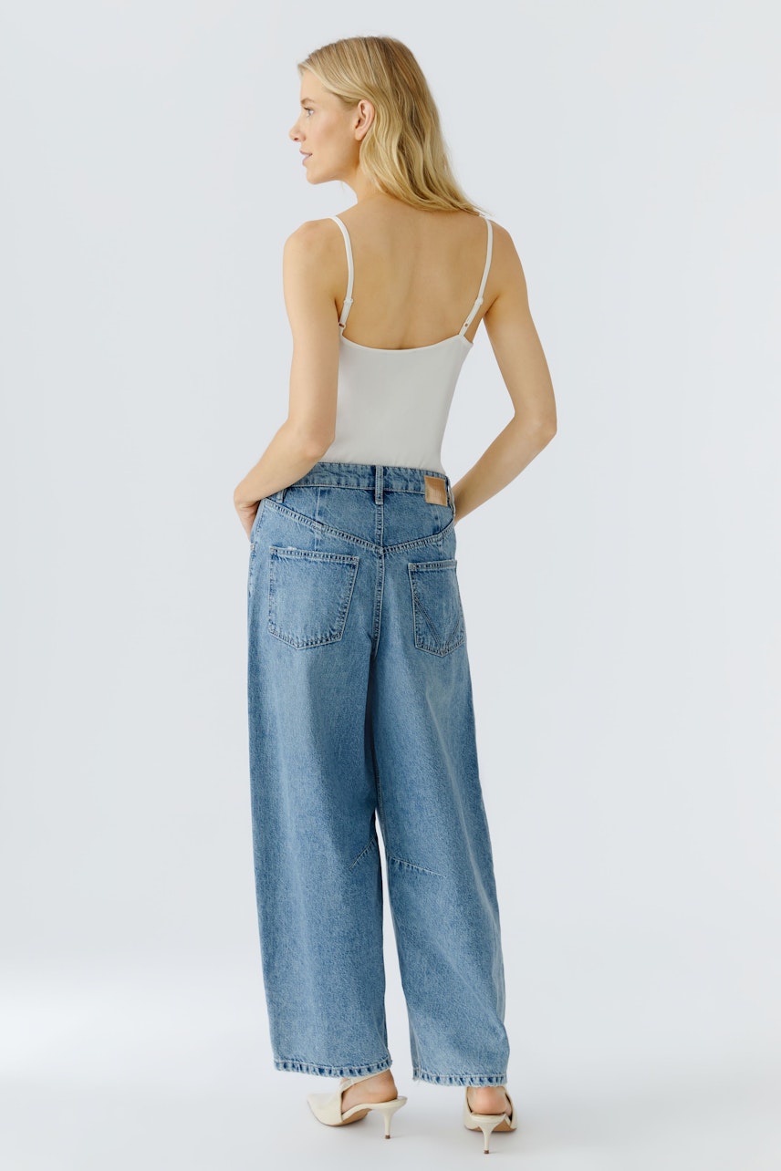 Bequeme Jeans Barrel: Frau trägt weite, hellblaue Jeans mit lässigem Schnitt und Rückenansicht.