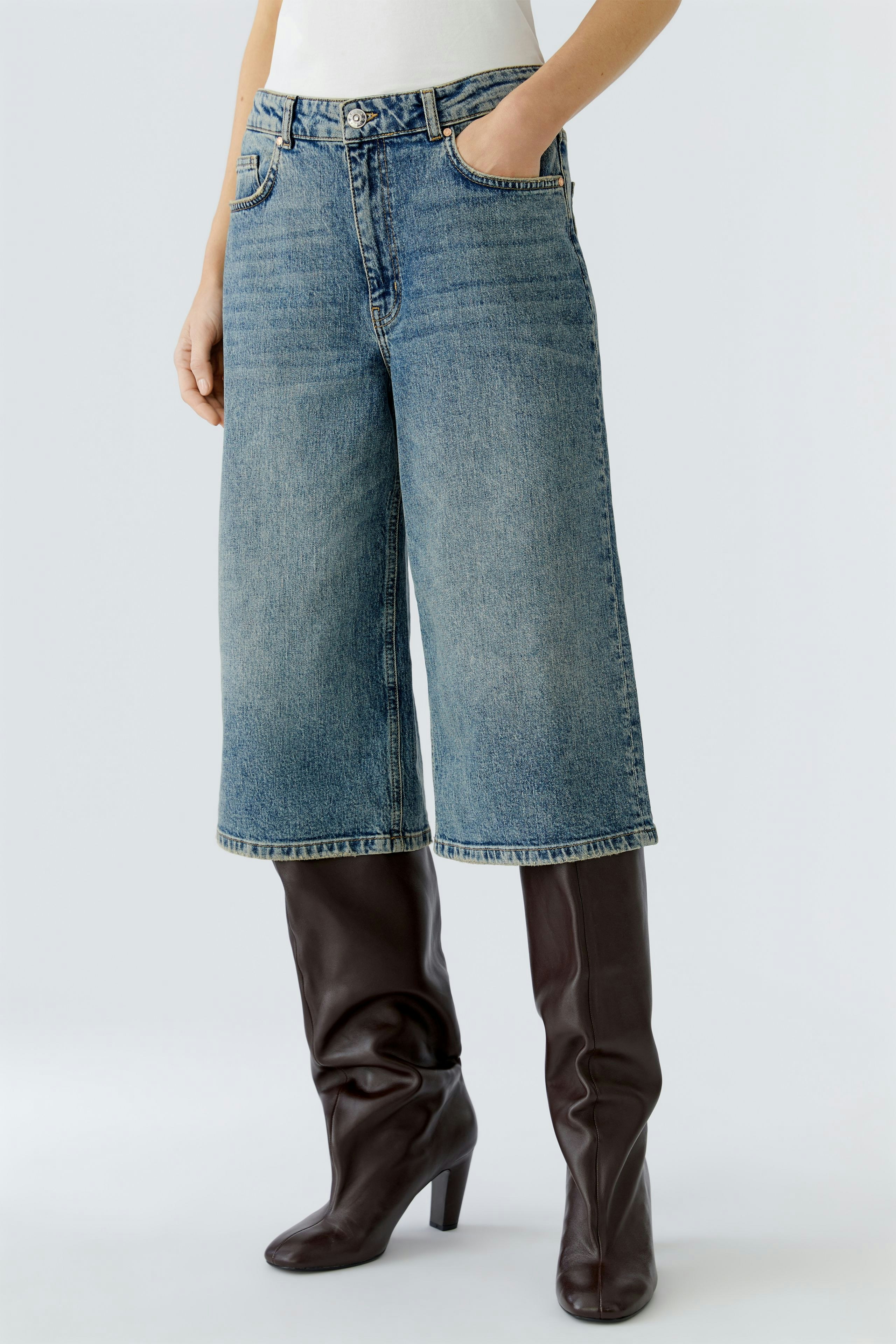 Casual women's jeans Bermuda: A woman in light blue Bermuda jeans with a relaxed fit and pockets.