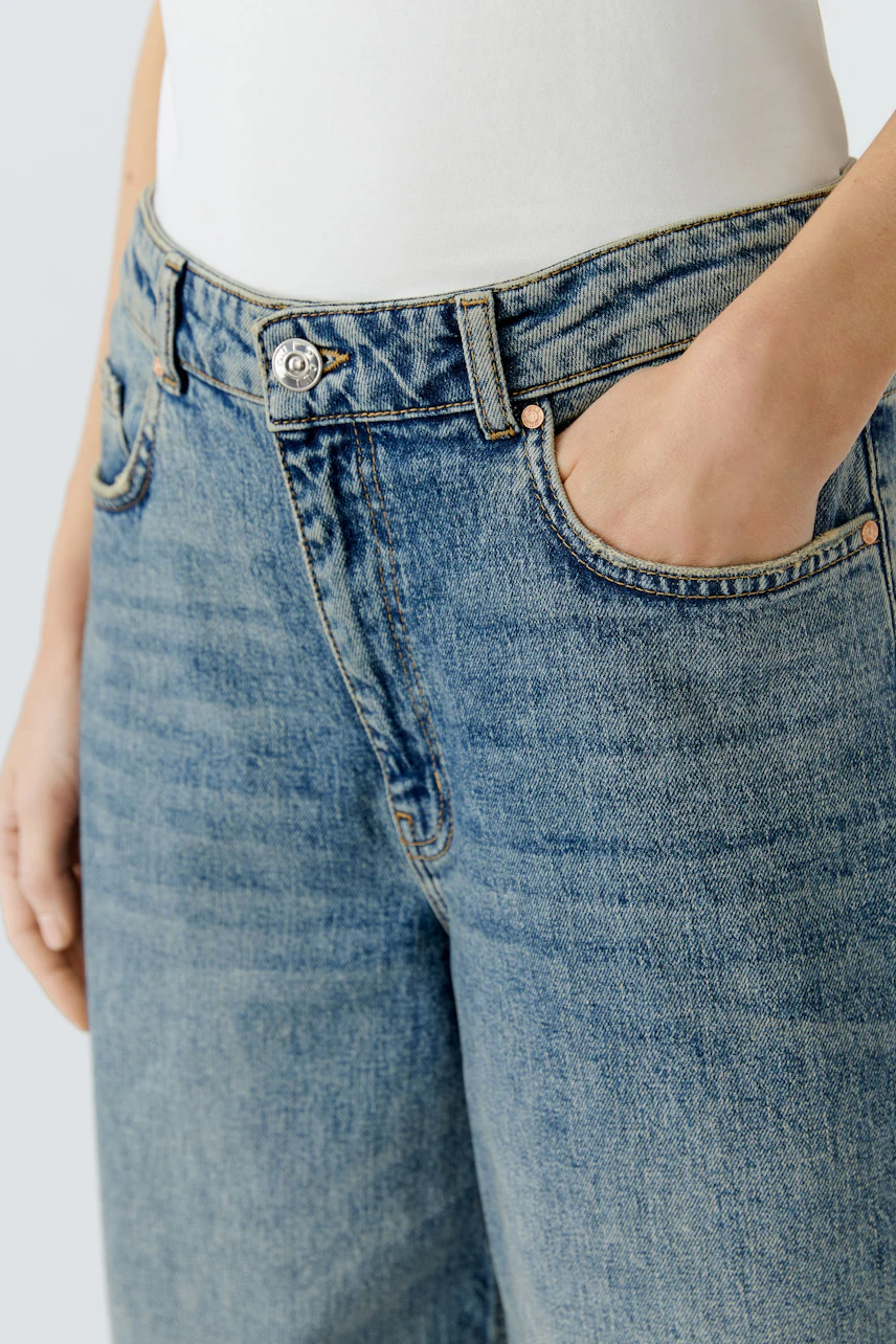 Casual women's jeans Bermuda: Close-up of a woman wearing light blue denim Bermuda shorts with pockets.