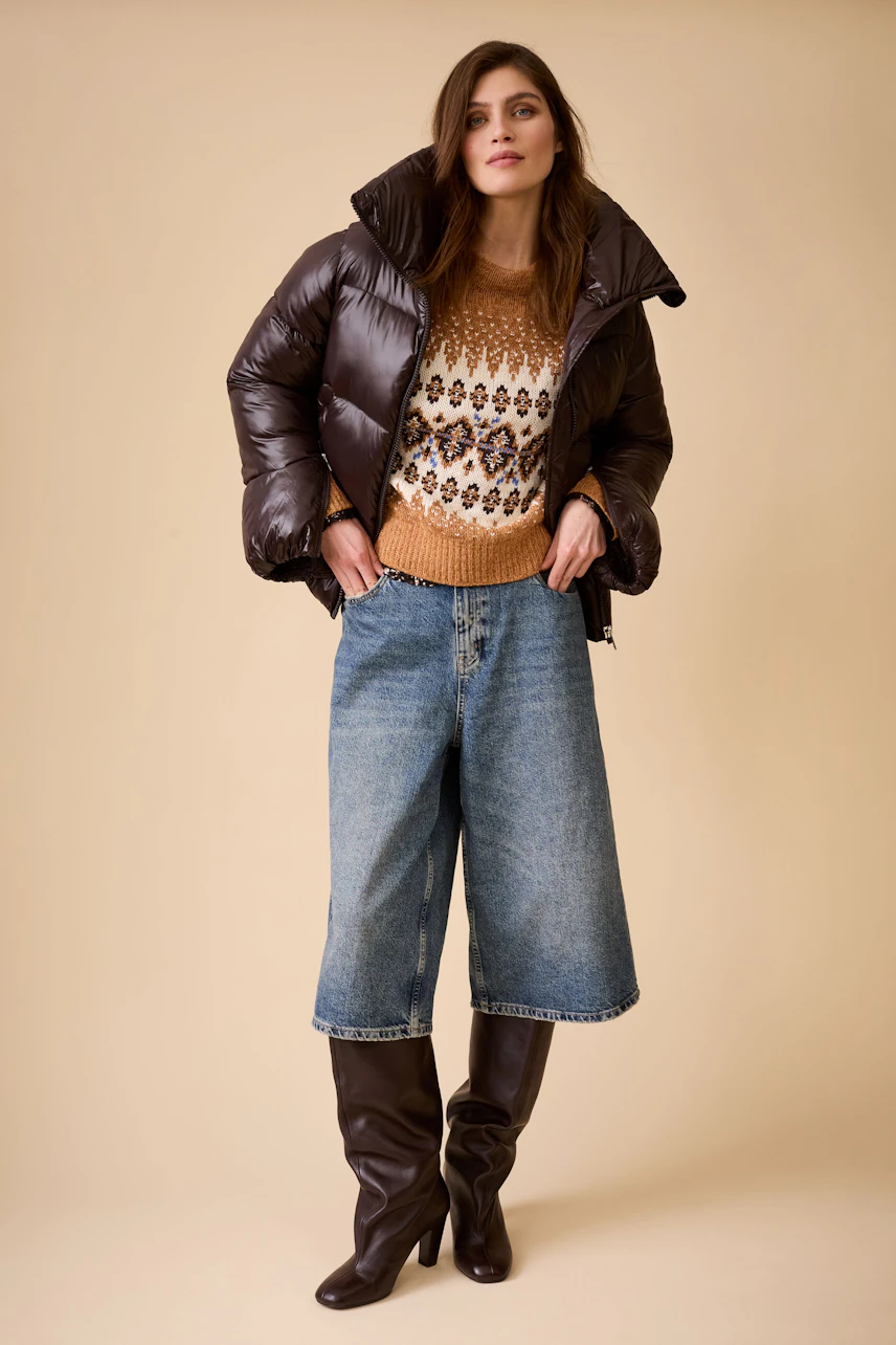 Casual women's Bermuda jeans: A woman in relaxed denim shorts paired with a cozy pullover and puffer jacket.