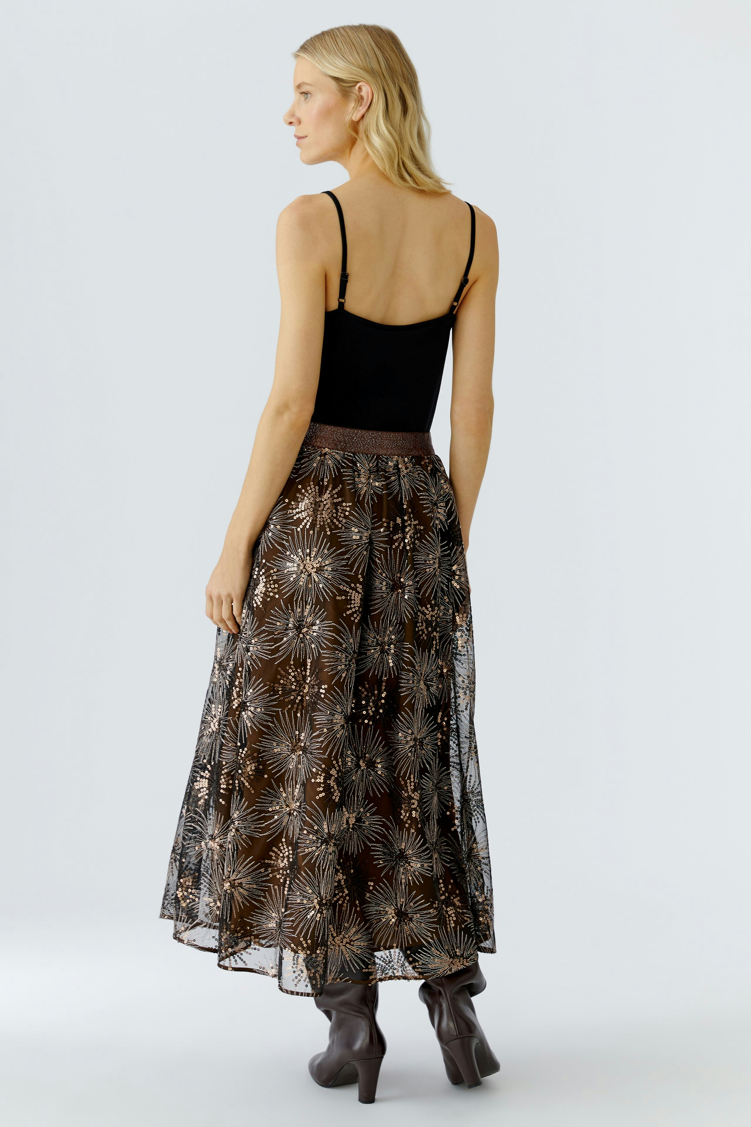 A-line skirt: Woman in a sheer, patterned skirt with a fitted top, showcasing a relaxed style.