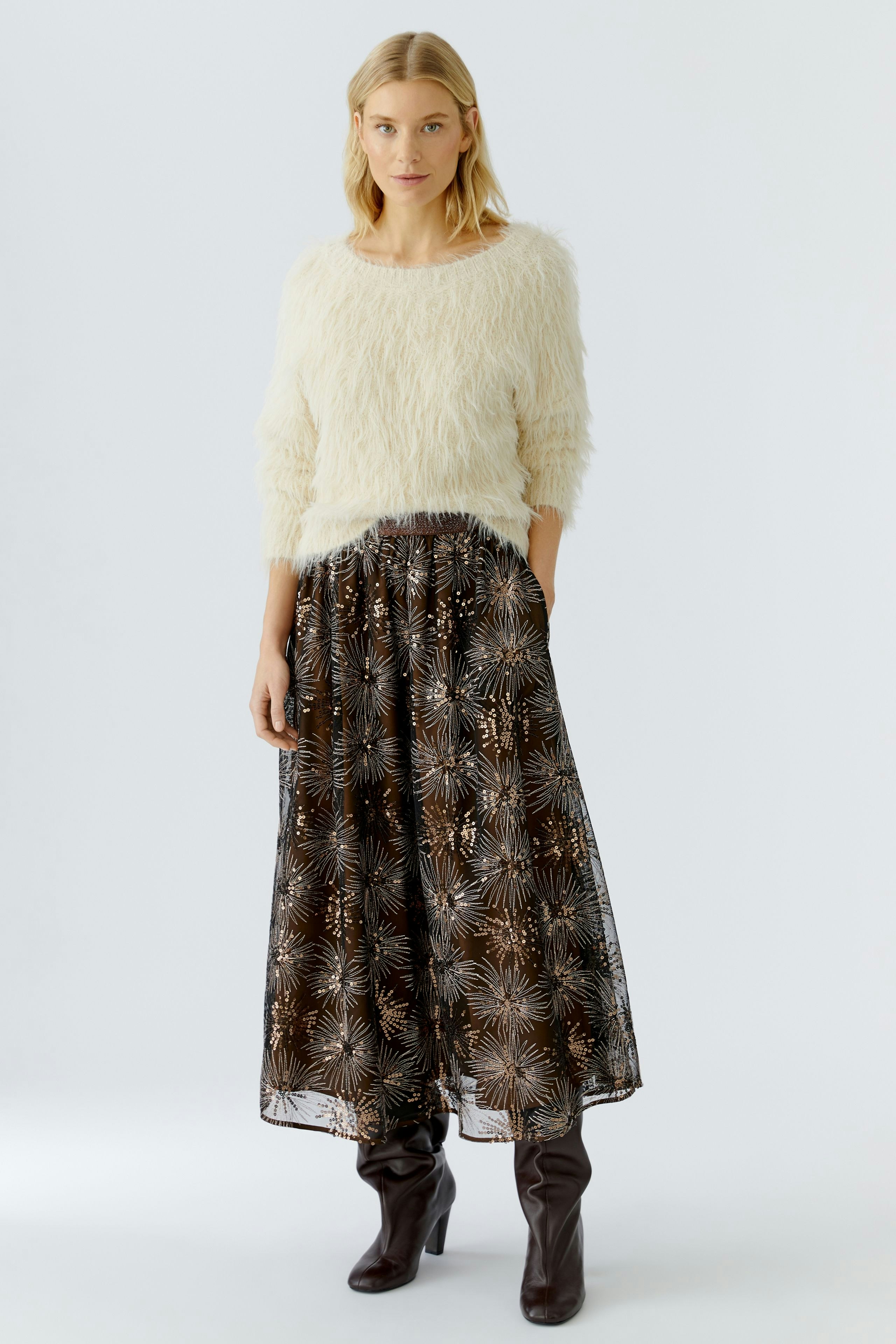 A-line skirt: Woman in a fluffy pullover and a patterned skirt, showcasing a relaxed style.