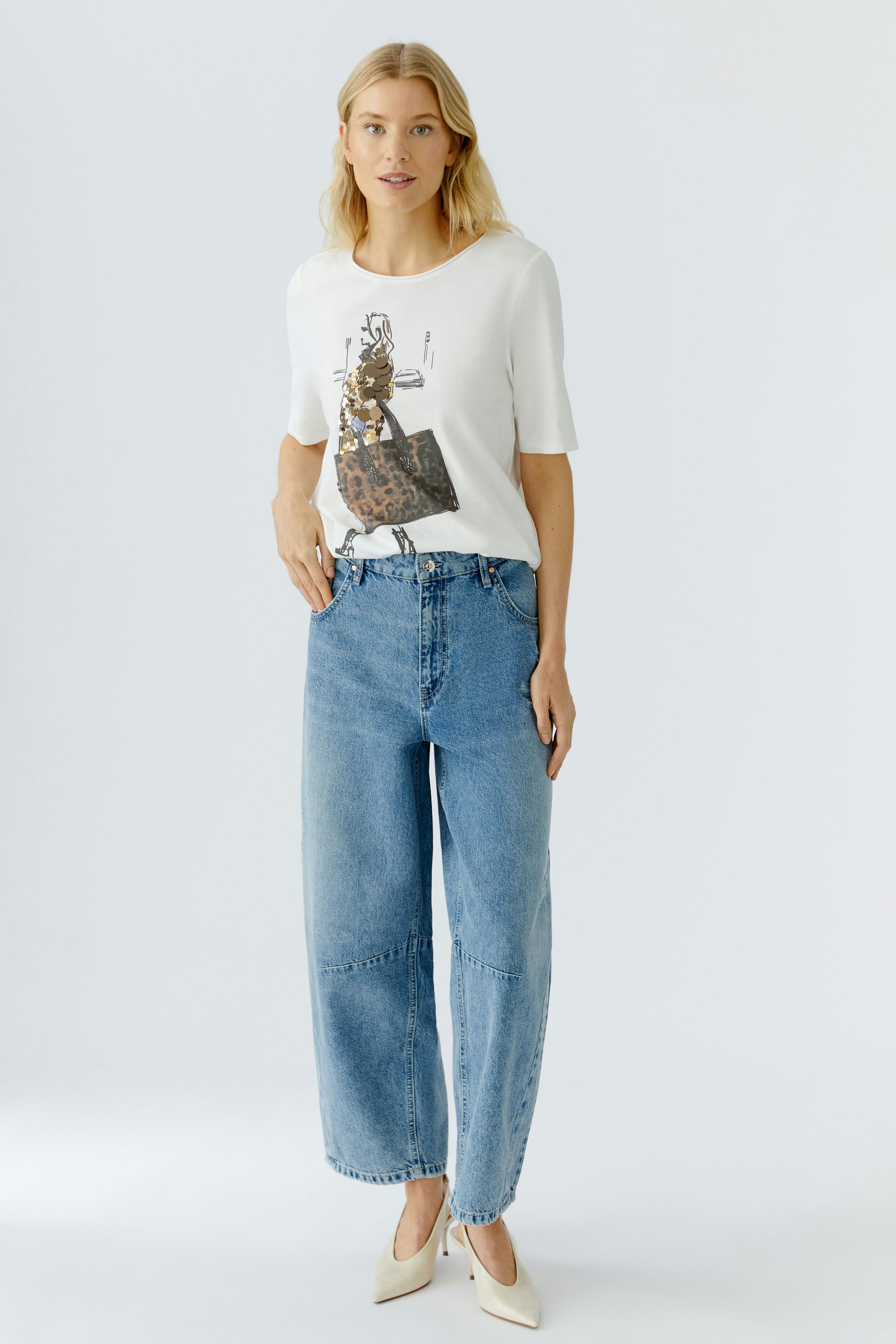 Casual women's T-shirt: A woman in a white tee with a playful graphic design, paired with relaxed jeans.