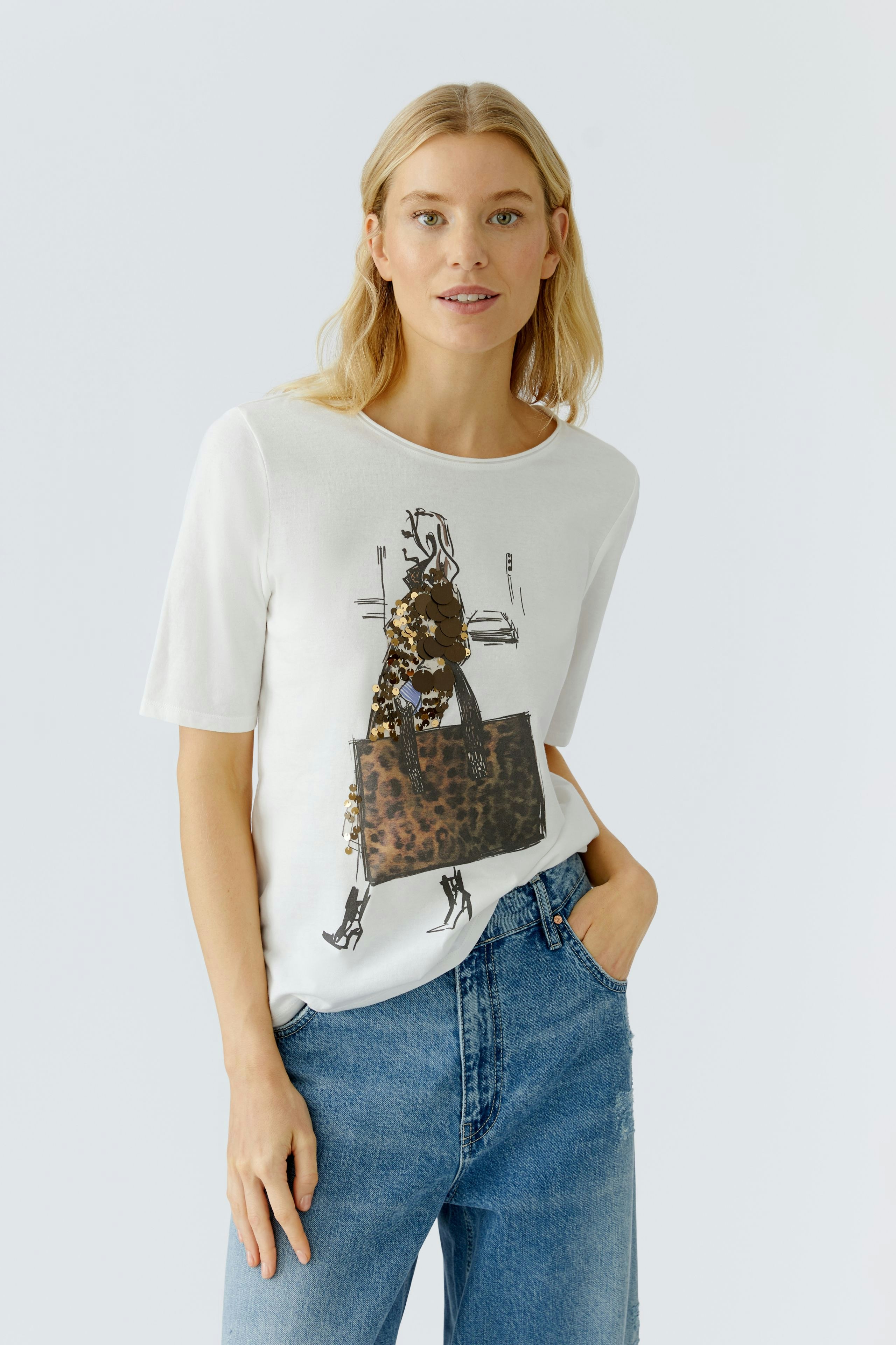 Casual women's T-shirt: Woman in a white tee with a stylish graphic and relaxed jeans.