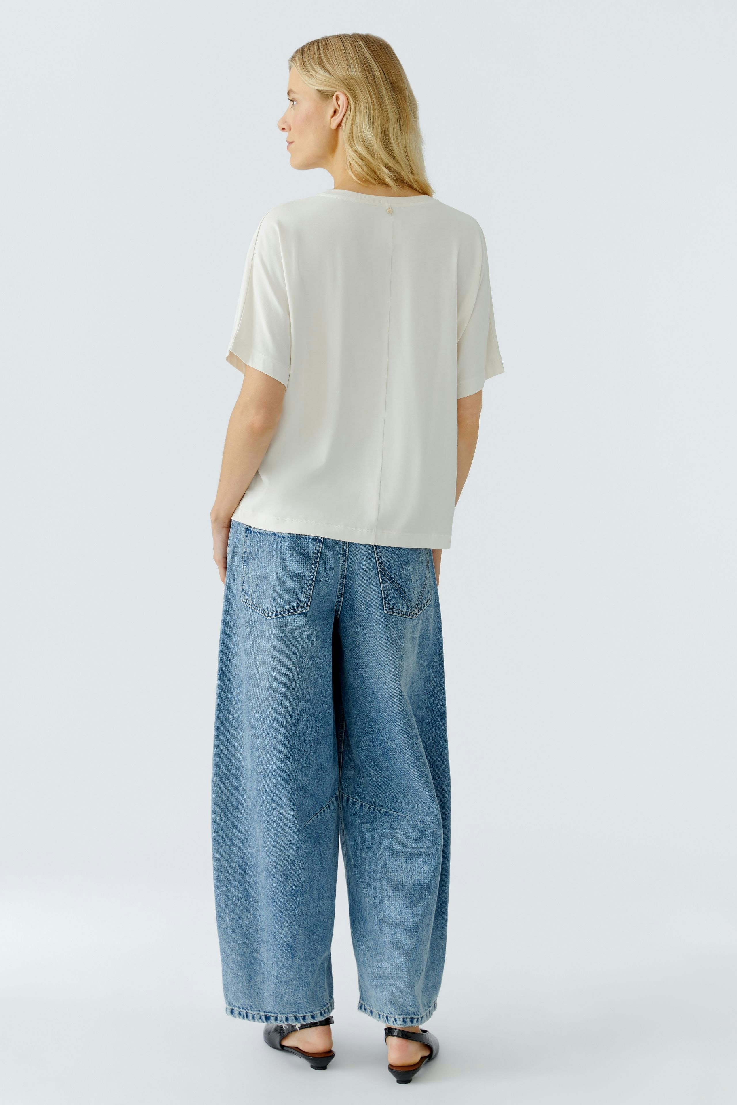 Casual women's T-shirt: Woman in a light top and wide jeans, showcasing a relaxed style.