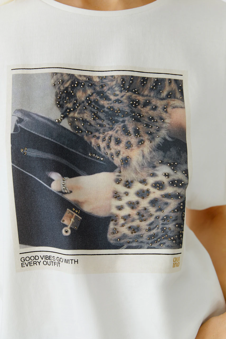 Damen-T-Shirt: Frau trägt ein weißes T-Shirt mit einem auffälligen Tiermotiv und lässigem Design.