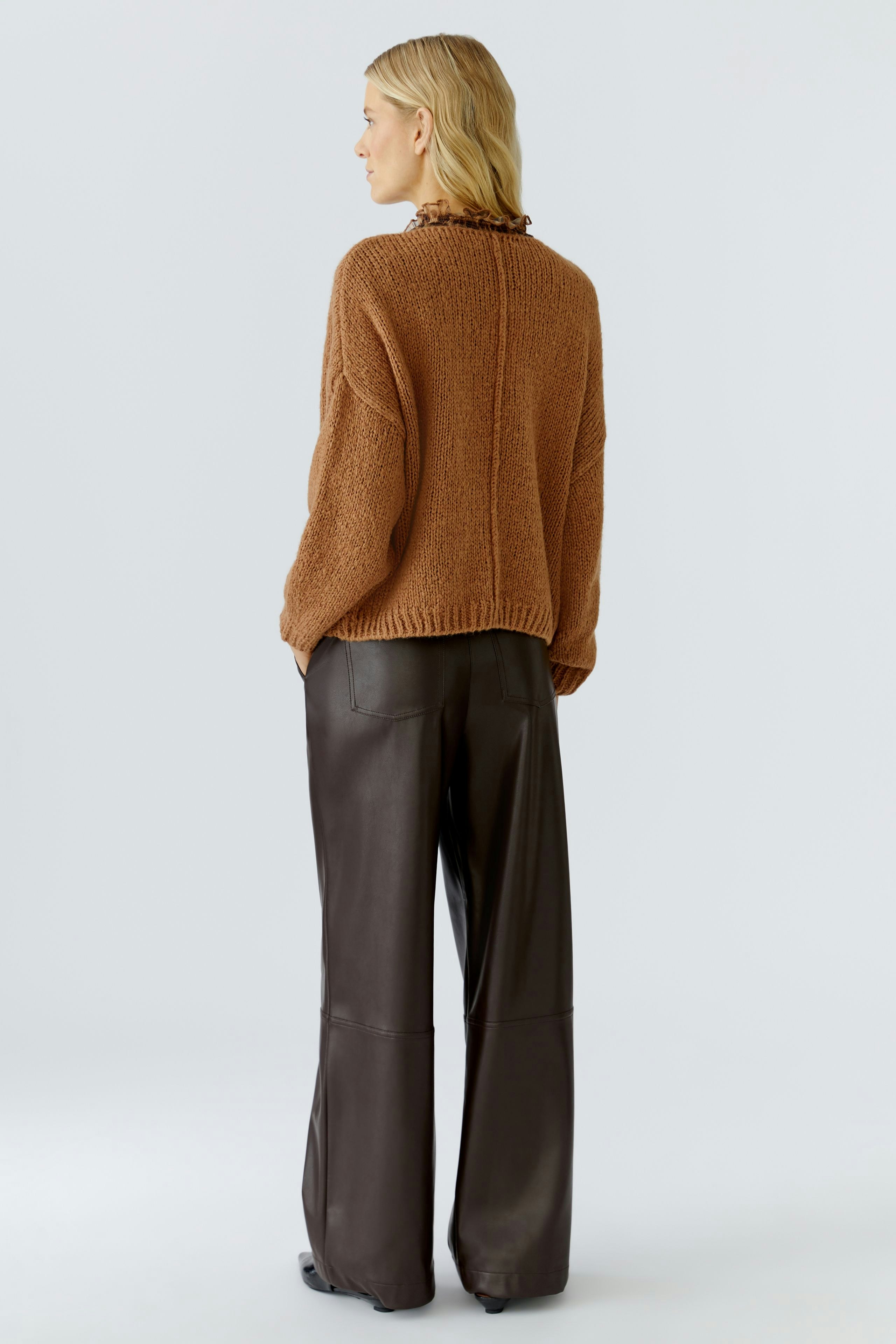 Casual women's pullover: A woman in a cozy brown pullover with a ruffled collar, paired with wide-leg pants.