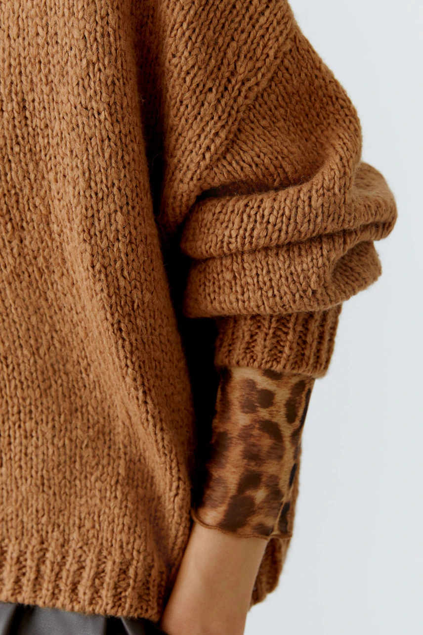 Casual women's pullover: A woman in a cozy brown knit pullover with rolled sleeves.