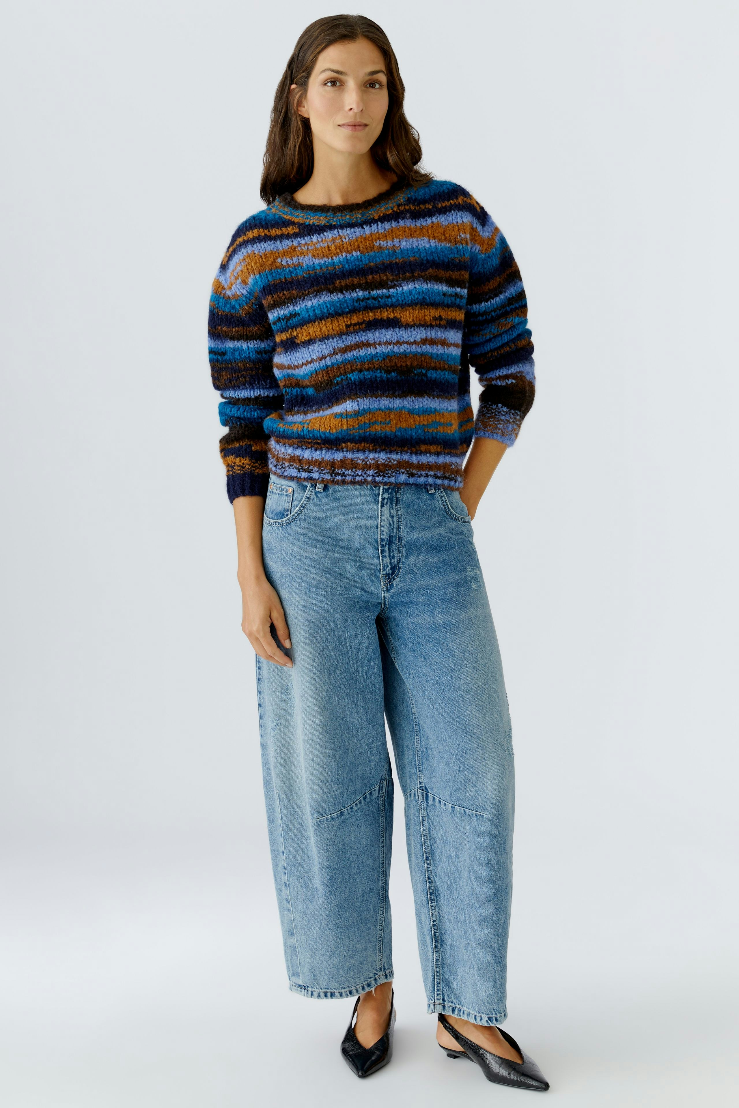 Casual women's pullover: Woman in a colorful striped pullover paired with relaxed-fit jeans.