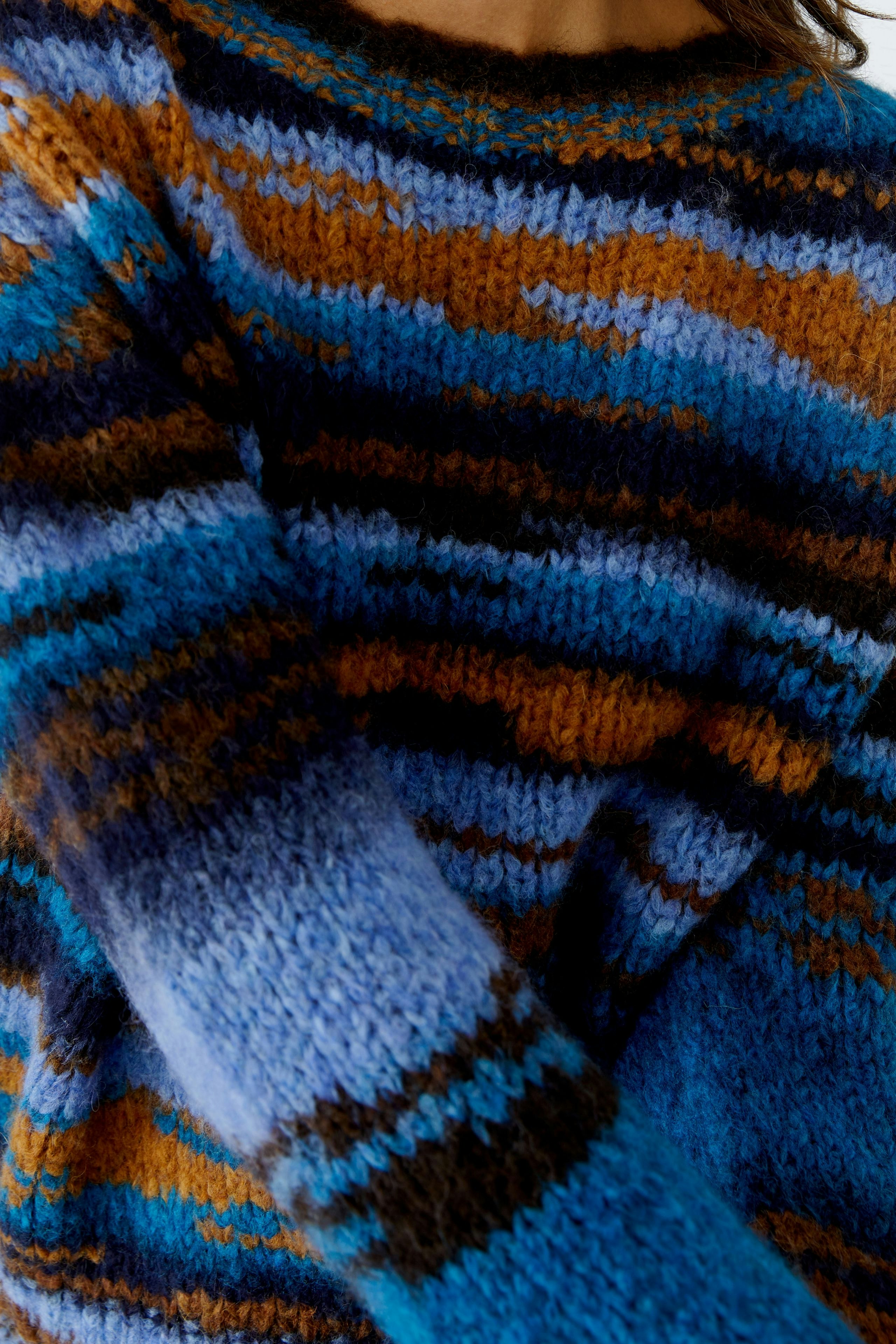Colorful women's pullover with a striped pattern, featuring shades of blue and brown.