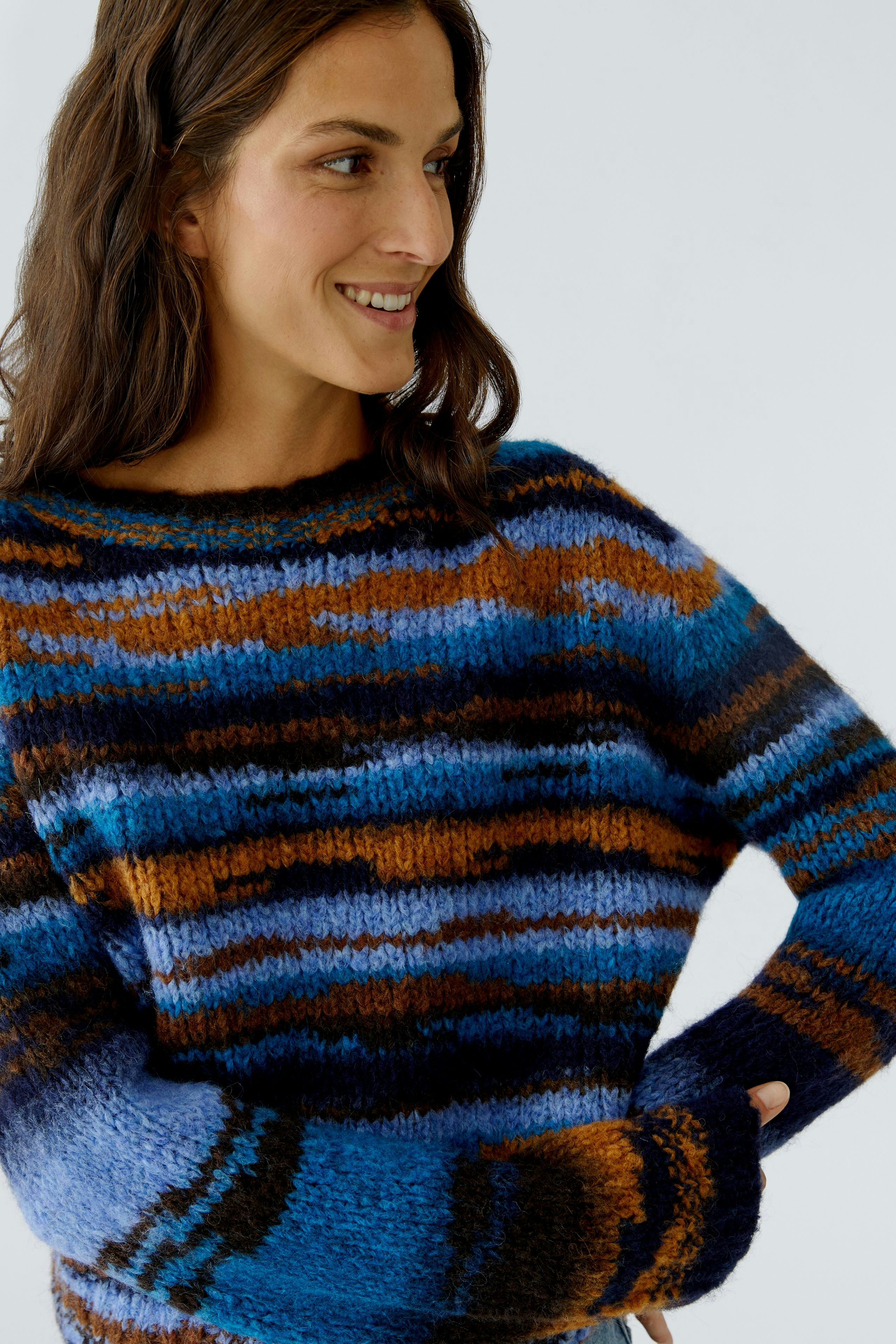 Casual women's pullover: Smiling woman in a colorful striped pullover with relaxed fit.