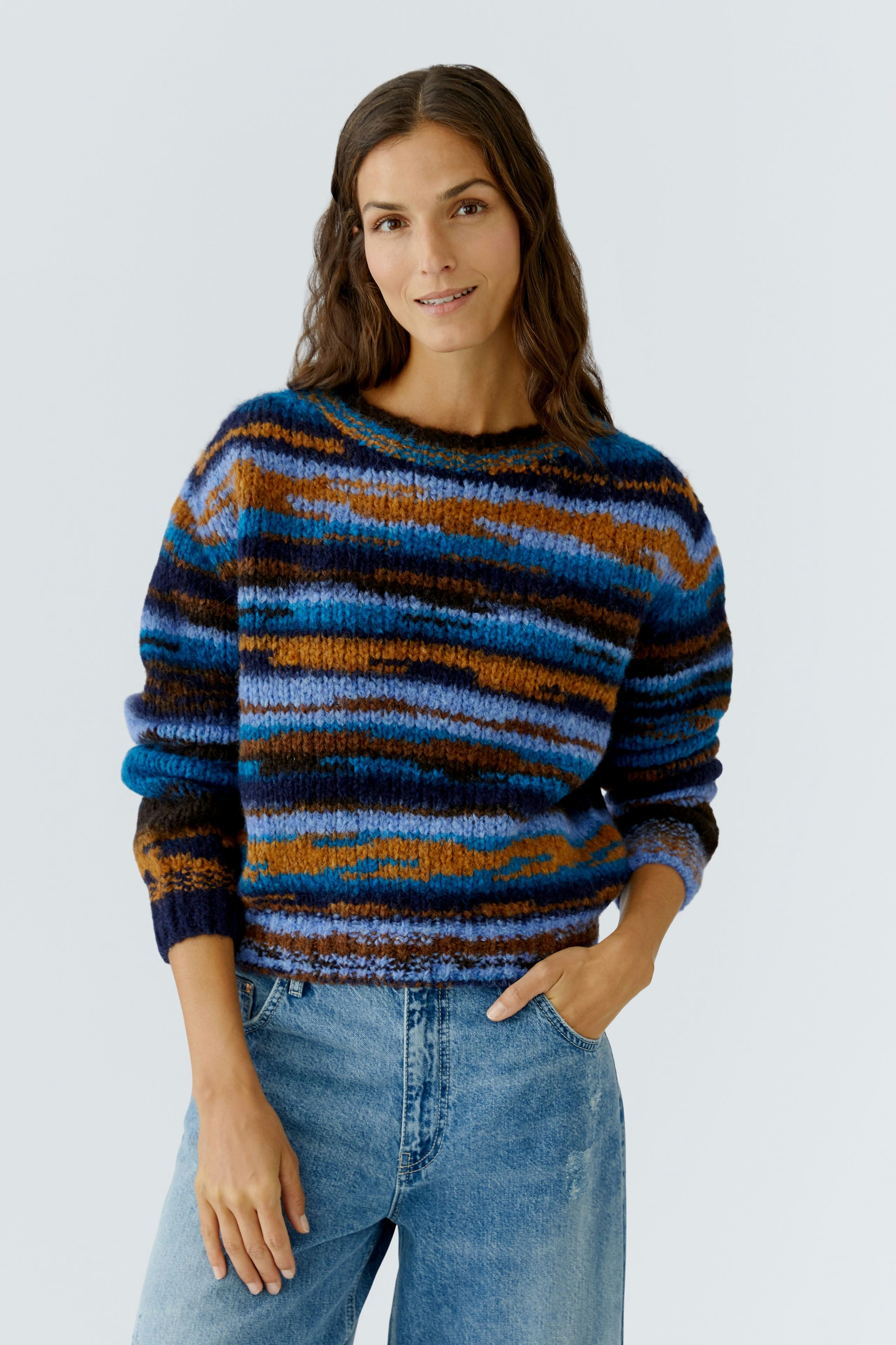 Casual women's pullover: A woman in a colorful striped pullover paired with relaxed jeans smiles confidently.