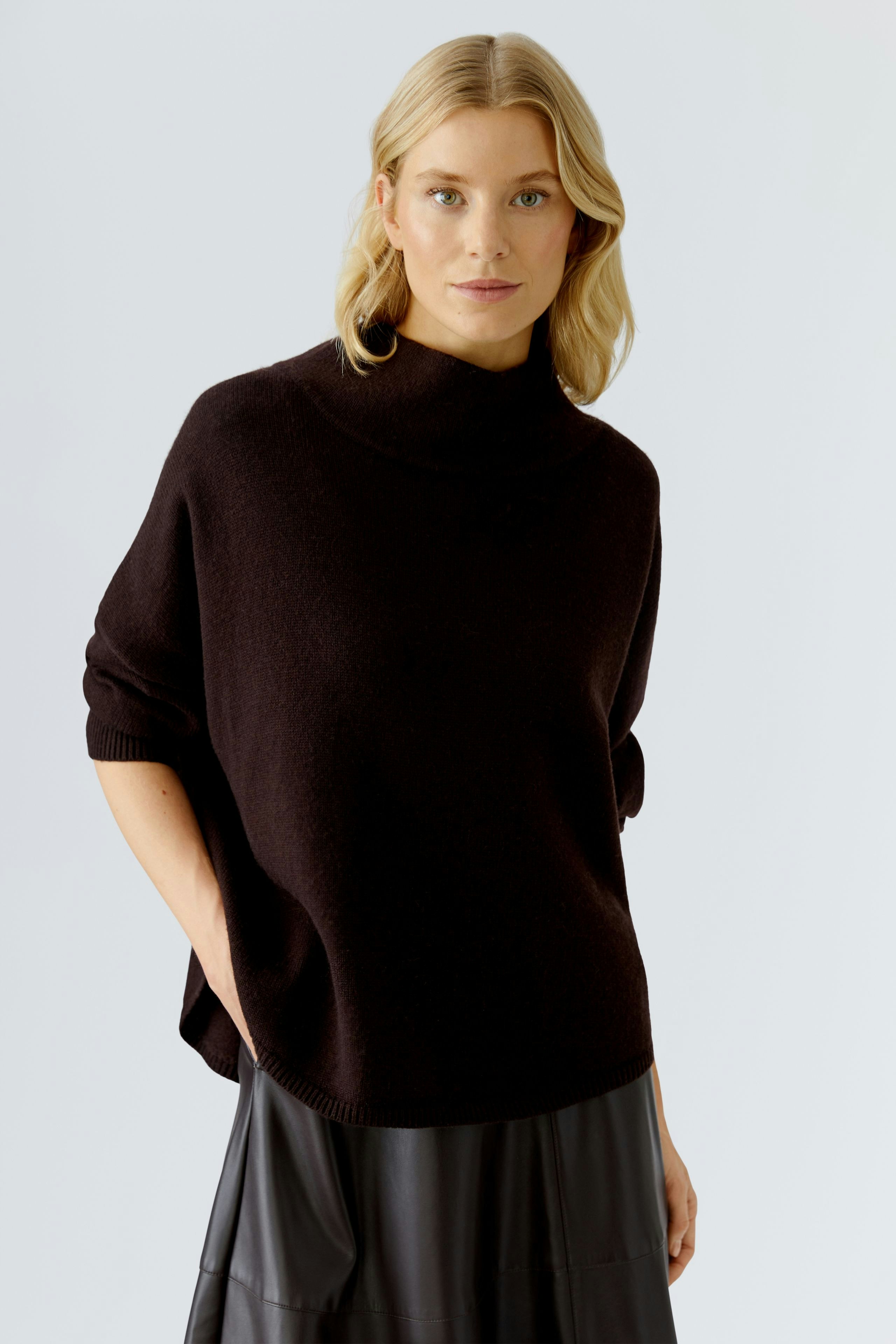 Casual women's pullover: A woman in a dark brown pullover with a relaxed fit and high collar.