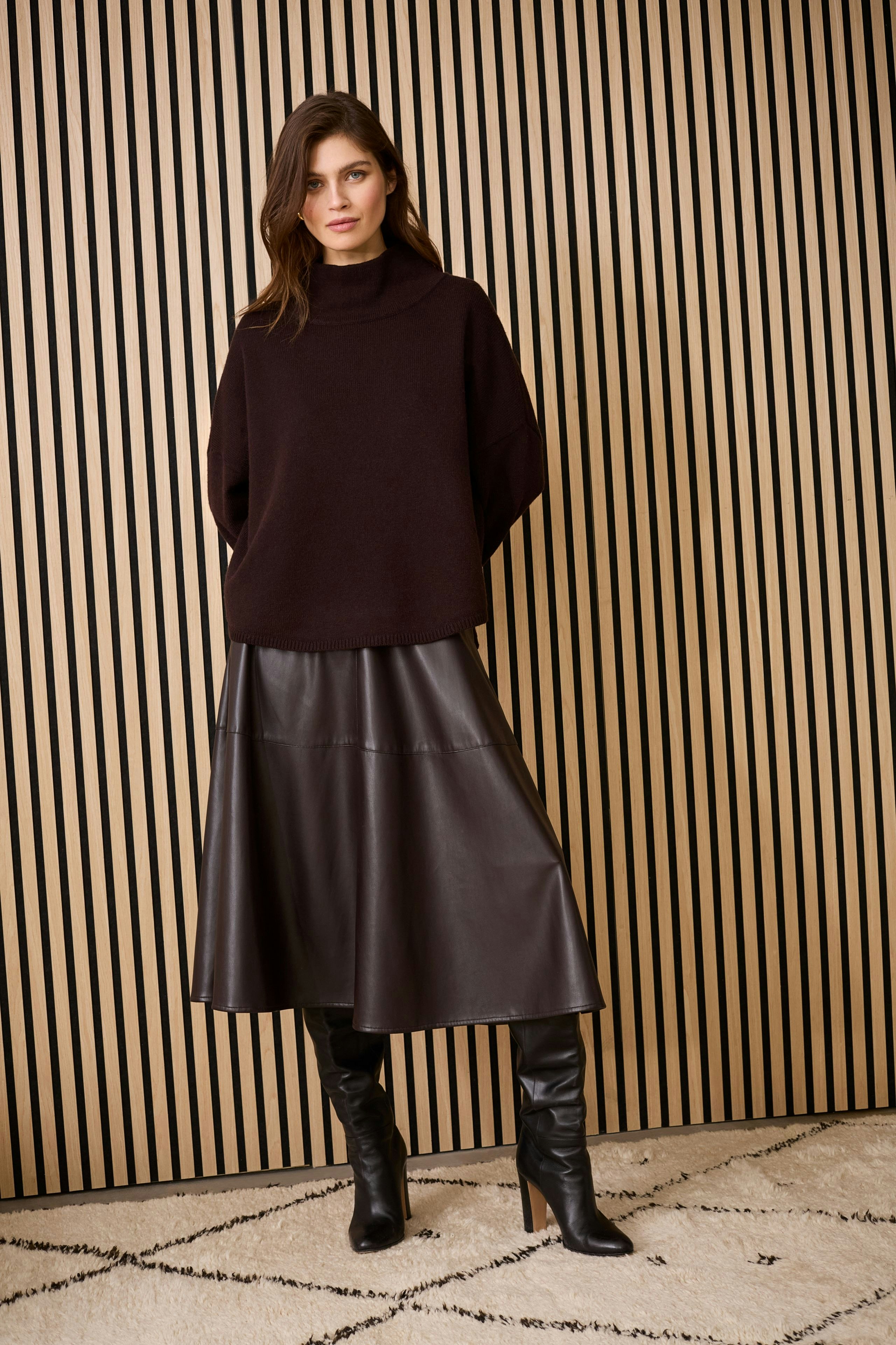 Casual women's pullover: A woman in a dark pullover paired with a leather skirt and knee-high boots.